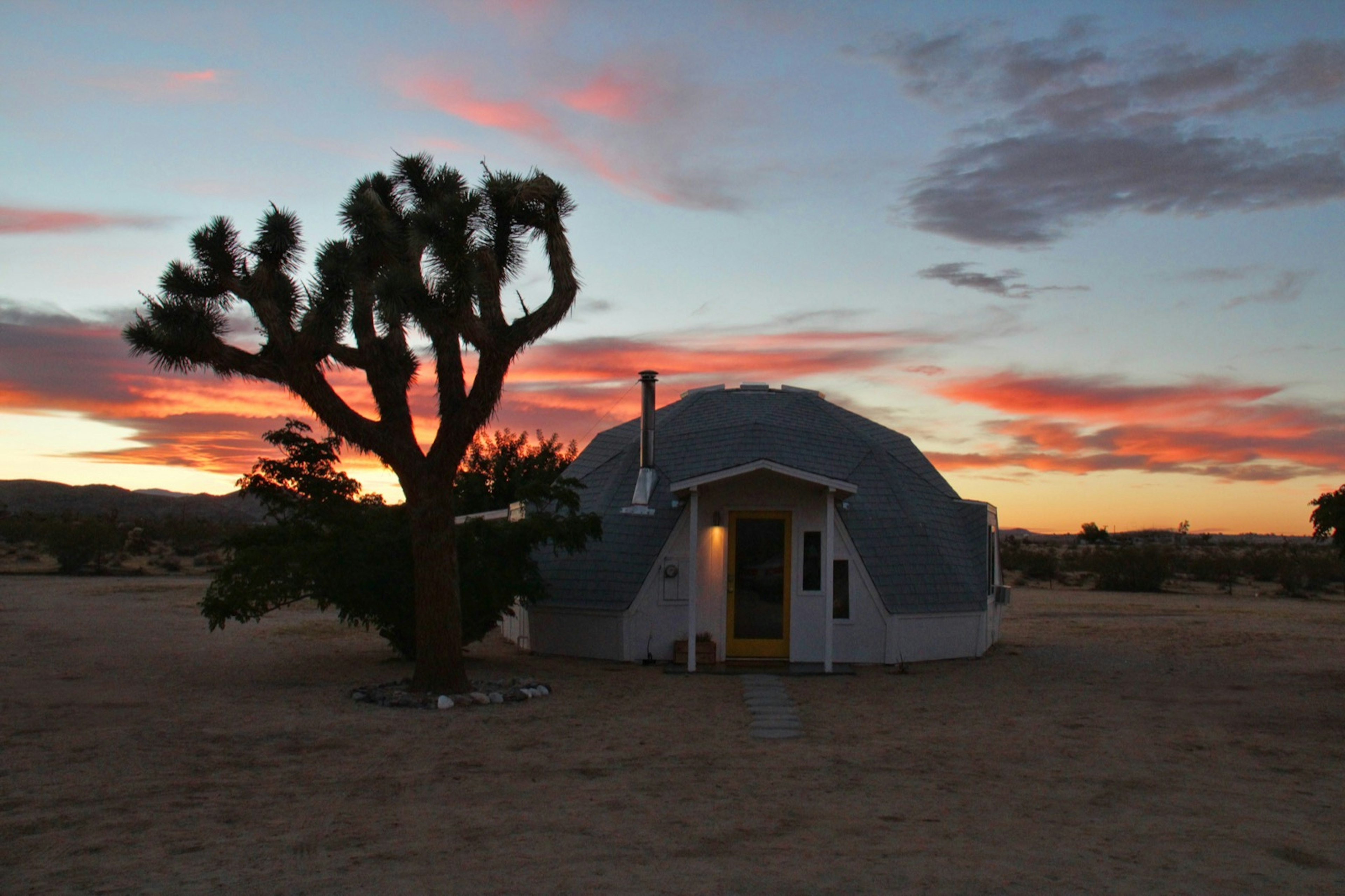 A geo-dome house in a desert next to a Joshua Tree