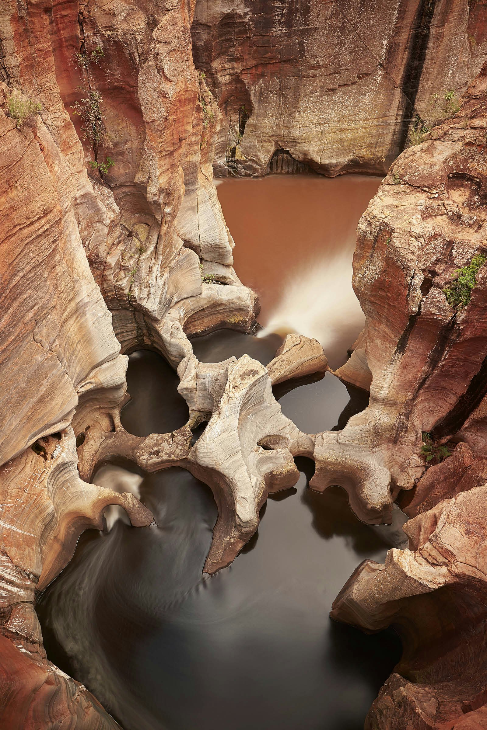 Reddish rock eroded into strange shapes at Bourke's Luck Potholes