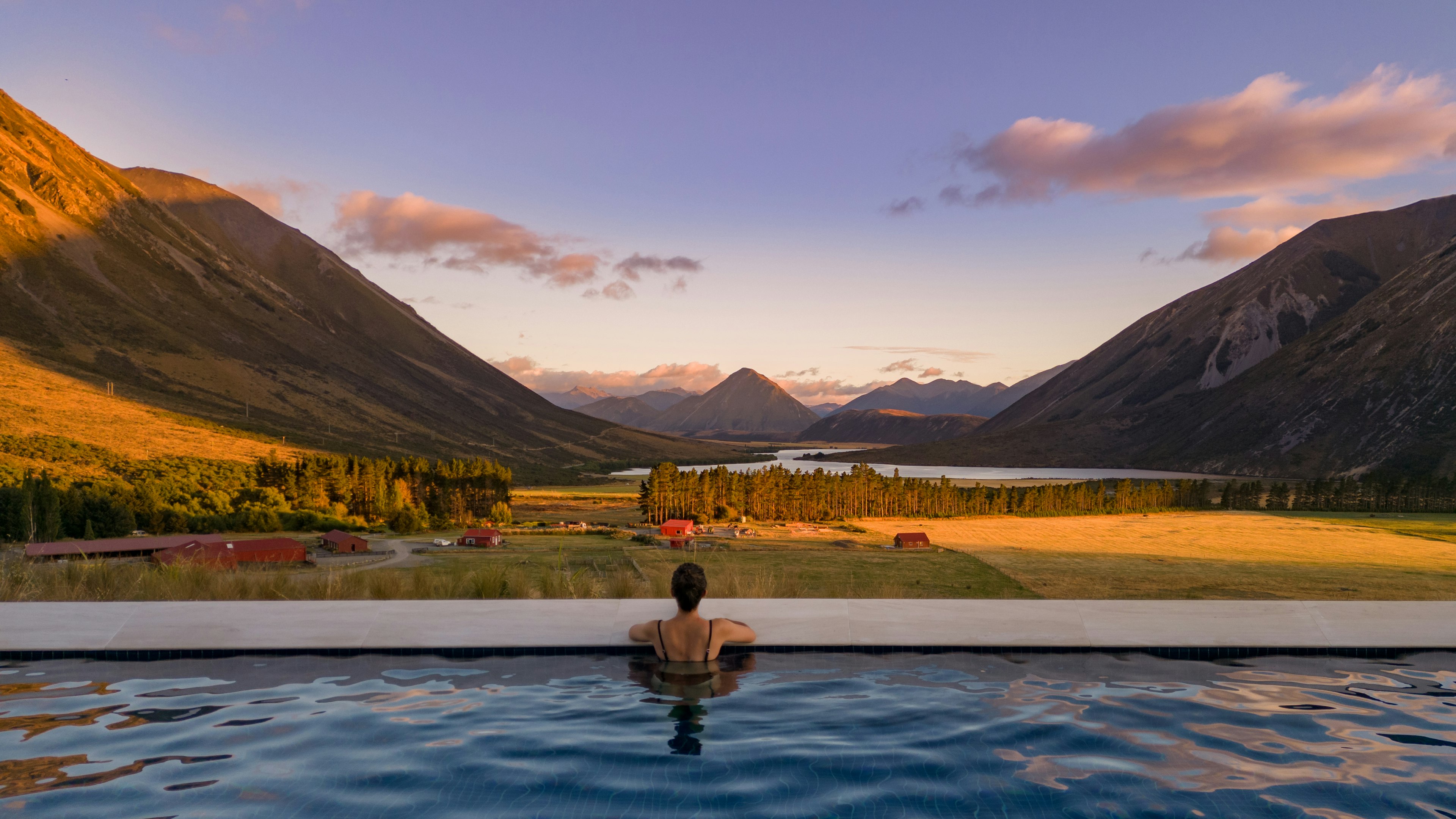 A woman looks out of infinity pool at Flockhill luxury lodge in NZ