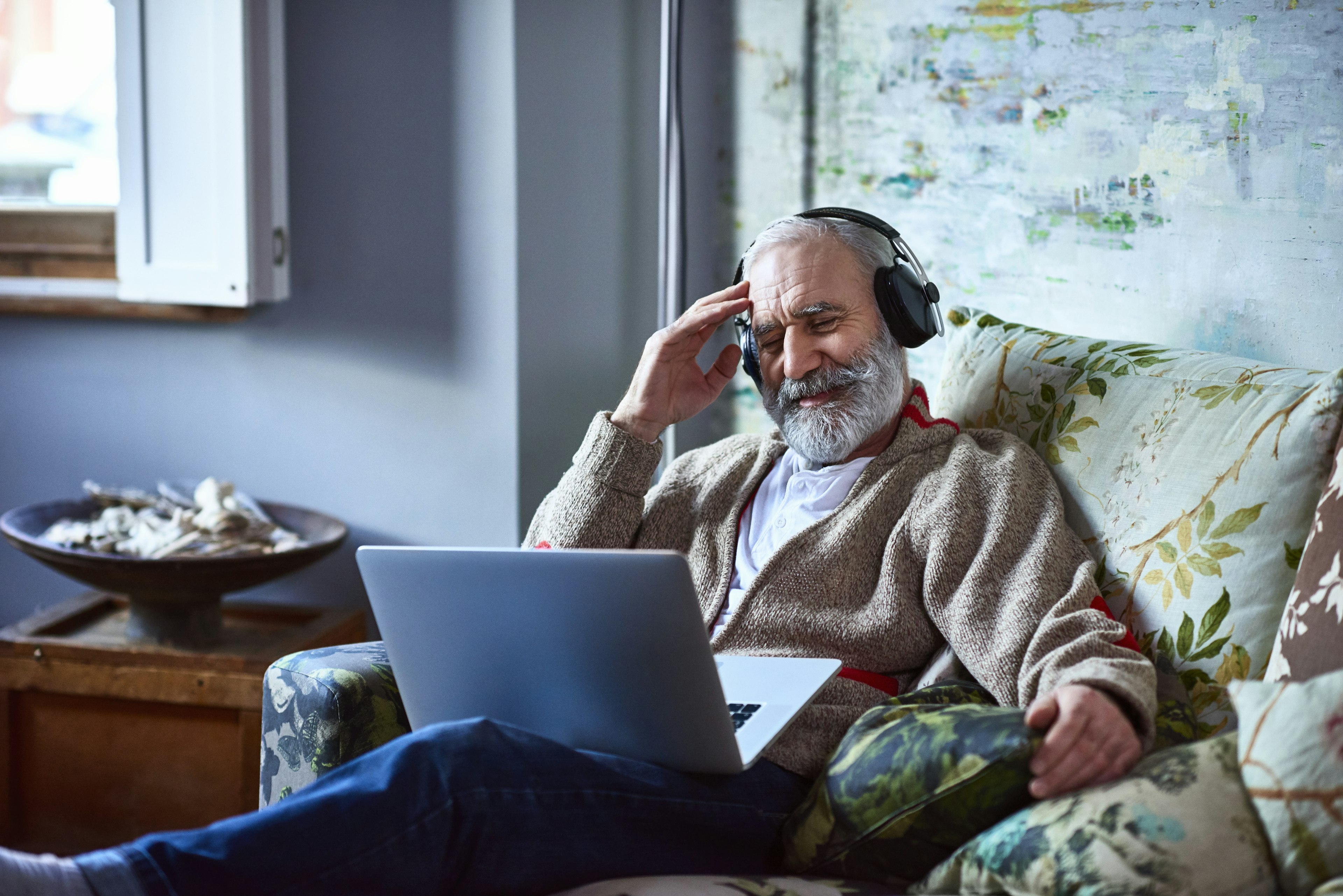 Portrait of an elderly man streaming movie on laptop wearing headphones