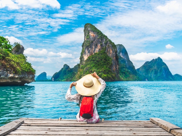A woman sits on a pier overlooking Phan Nga Bay in Thailand