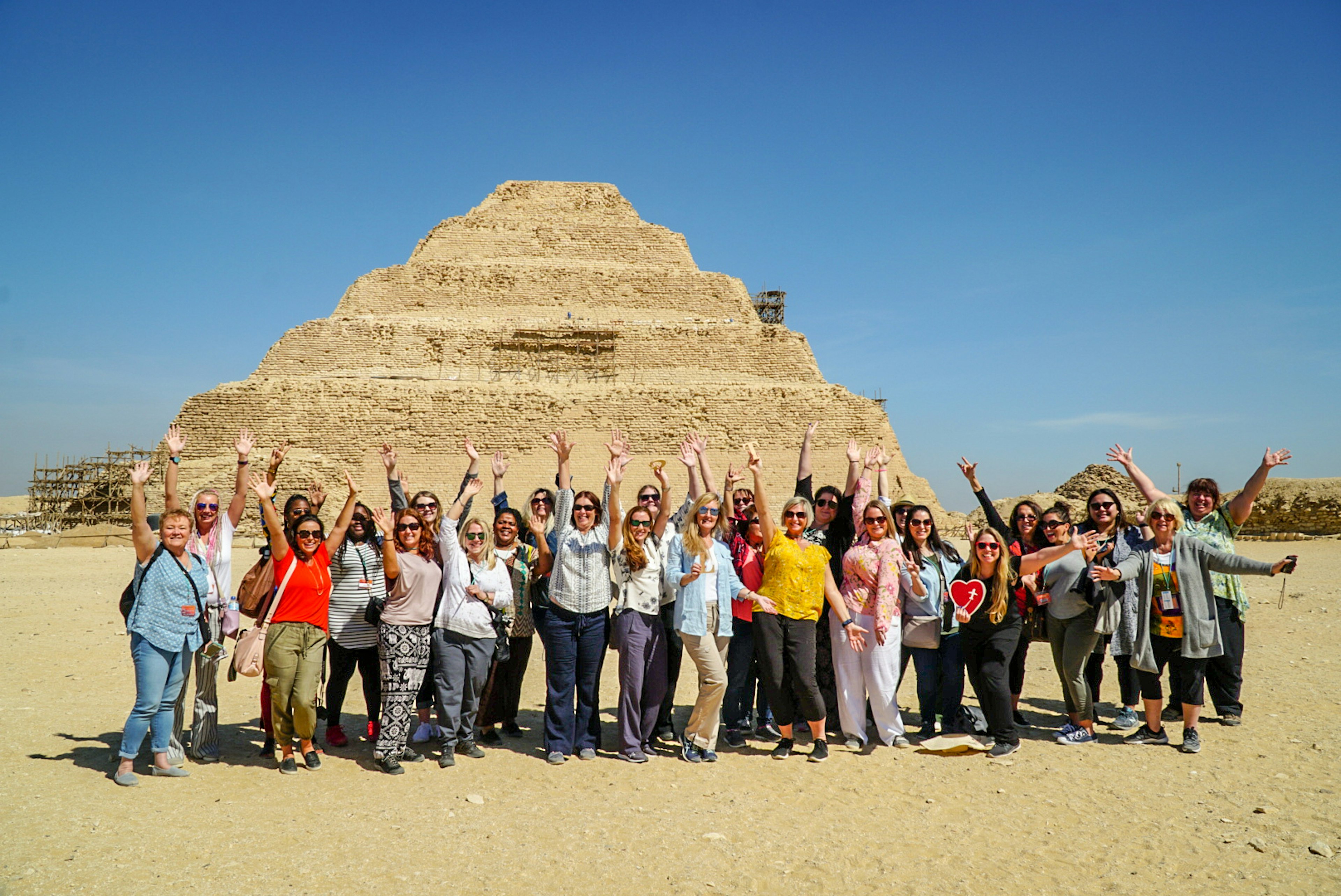 Women stand in front of a pyramid with their hands stretched into the air © Girls Love Travel