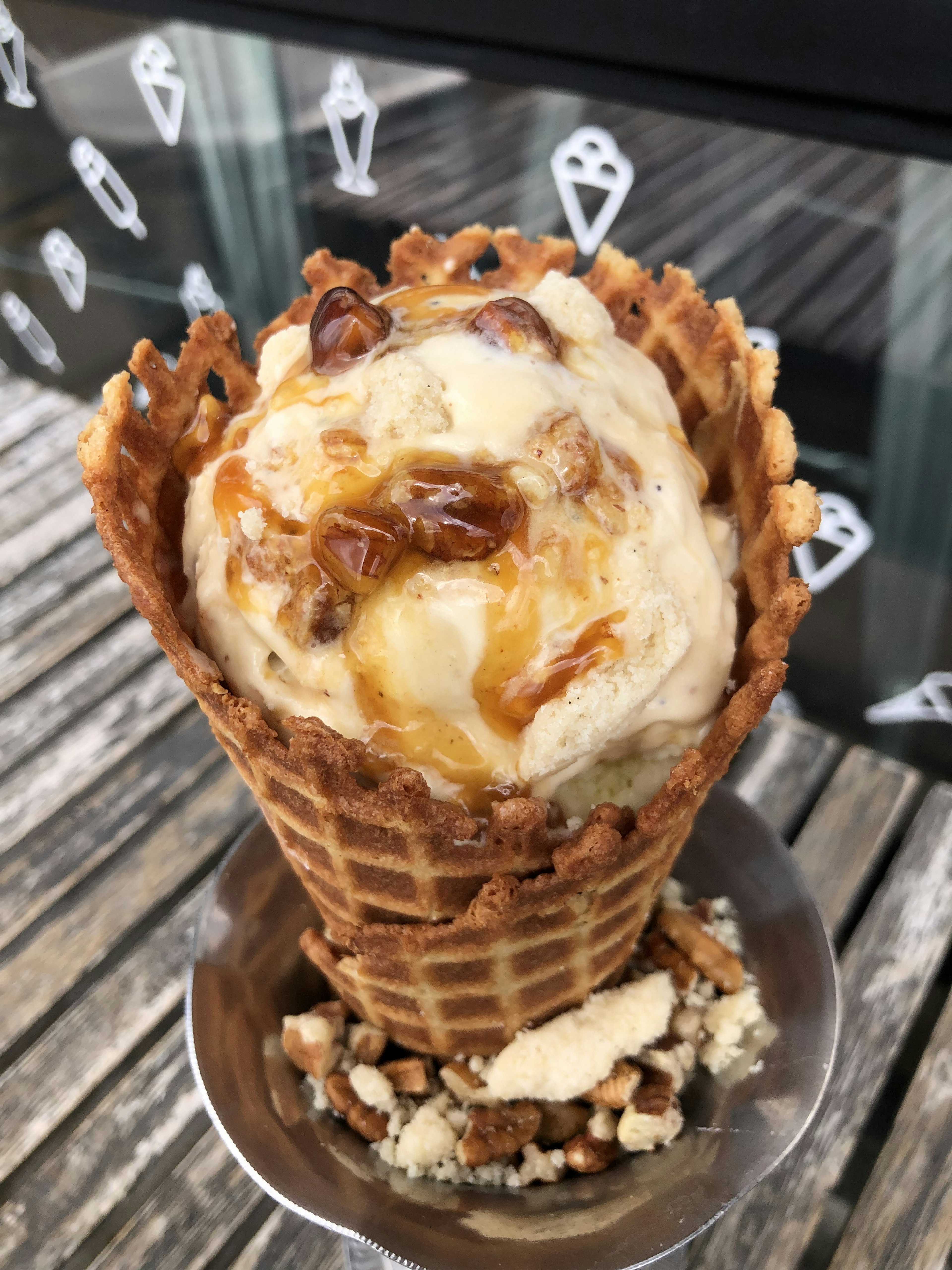 Closeup of a waffle cone filled with ice cream and drizzled with a praline sauce