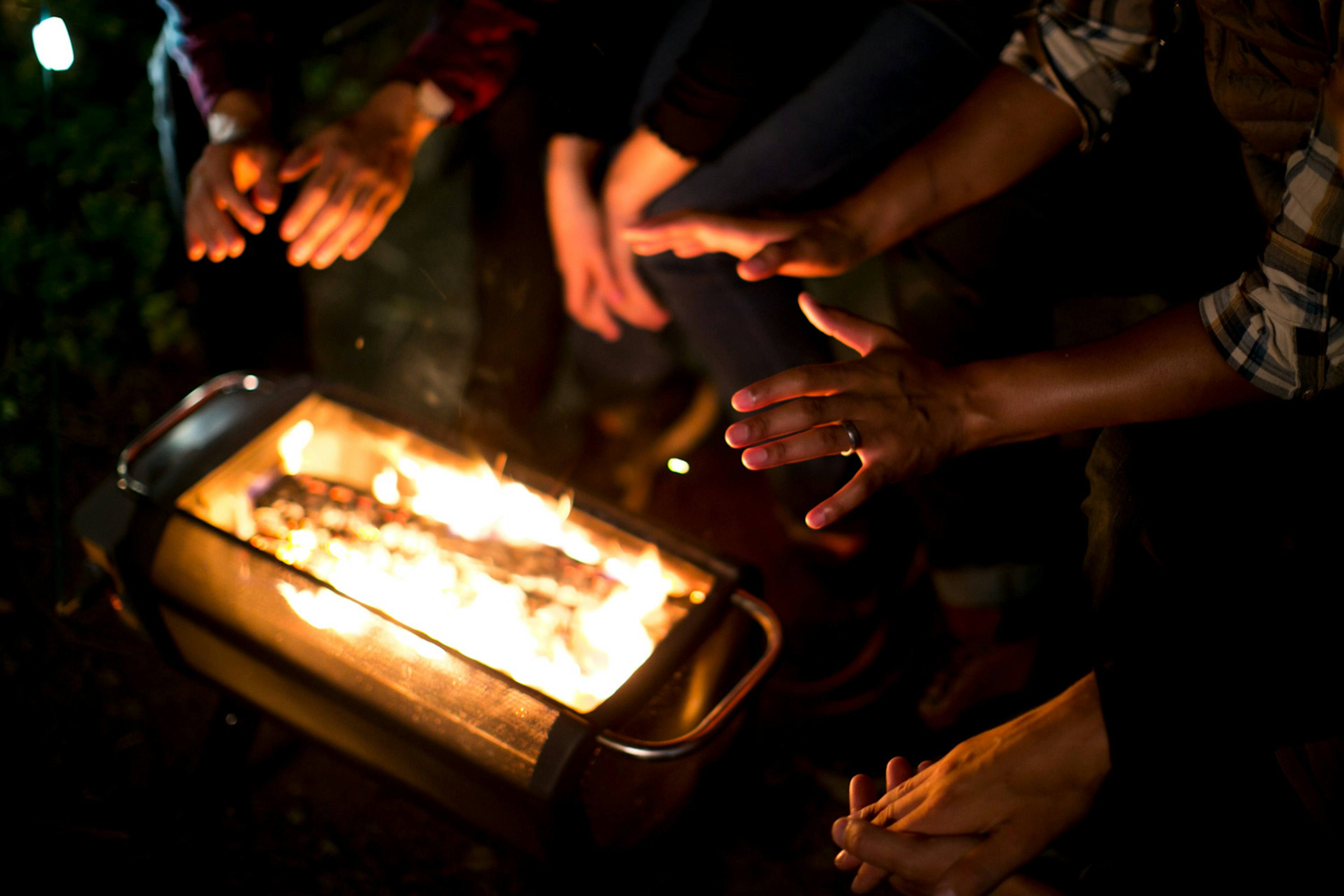 Warming hands over the BioLite FirePit at night