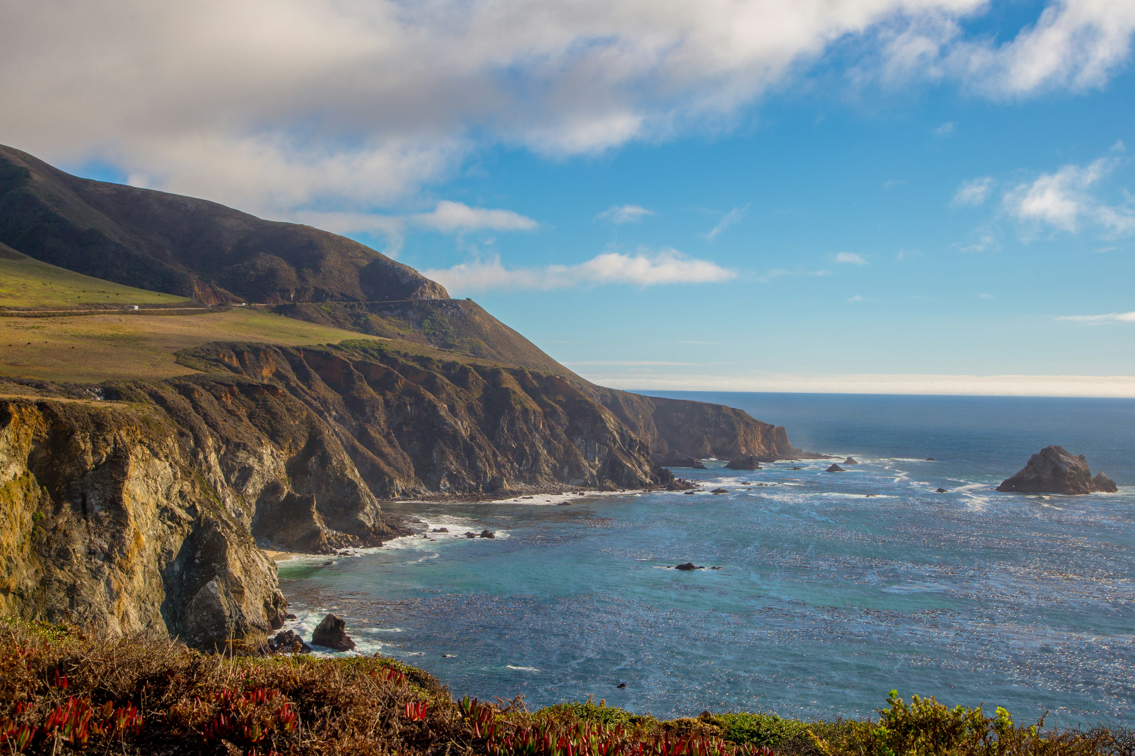 Highway one snakes around a cliff boarding the pacific ocean