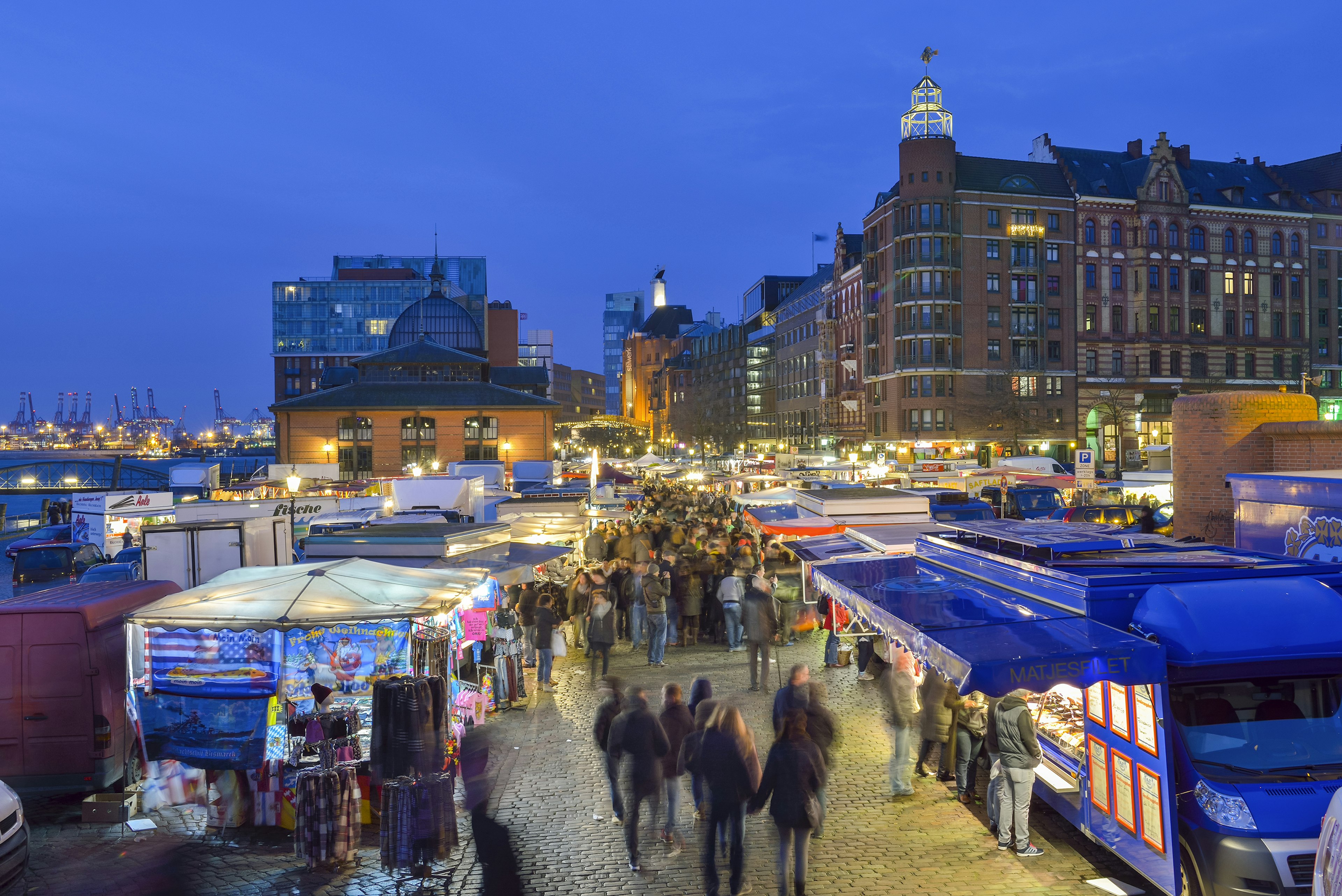 ""
634465647
morning, built structure, building, transportation, harbour, Market, market stall, sky, outdoor, landmark, fish market, water, River, elbe river, tourism, City Break, Long Exposure, St. Pauli, Port of Hamburg, twilight, morning twilight, Blue Hour, people, group of people, Large Group of People, Germany, Hamburg