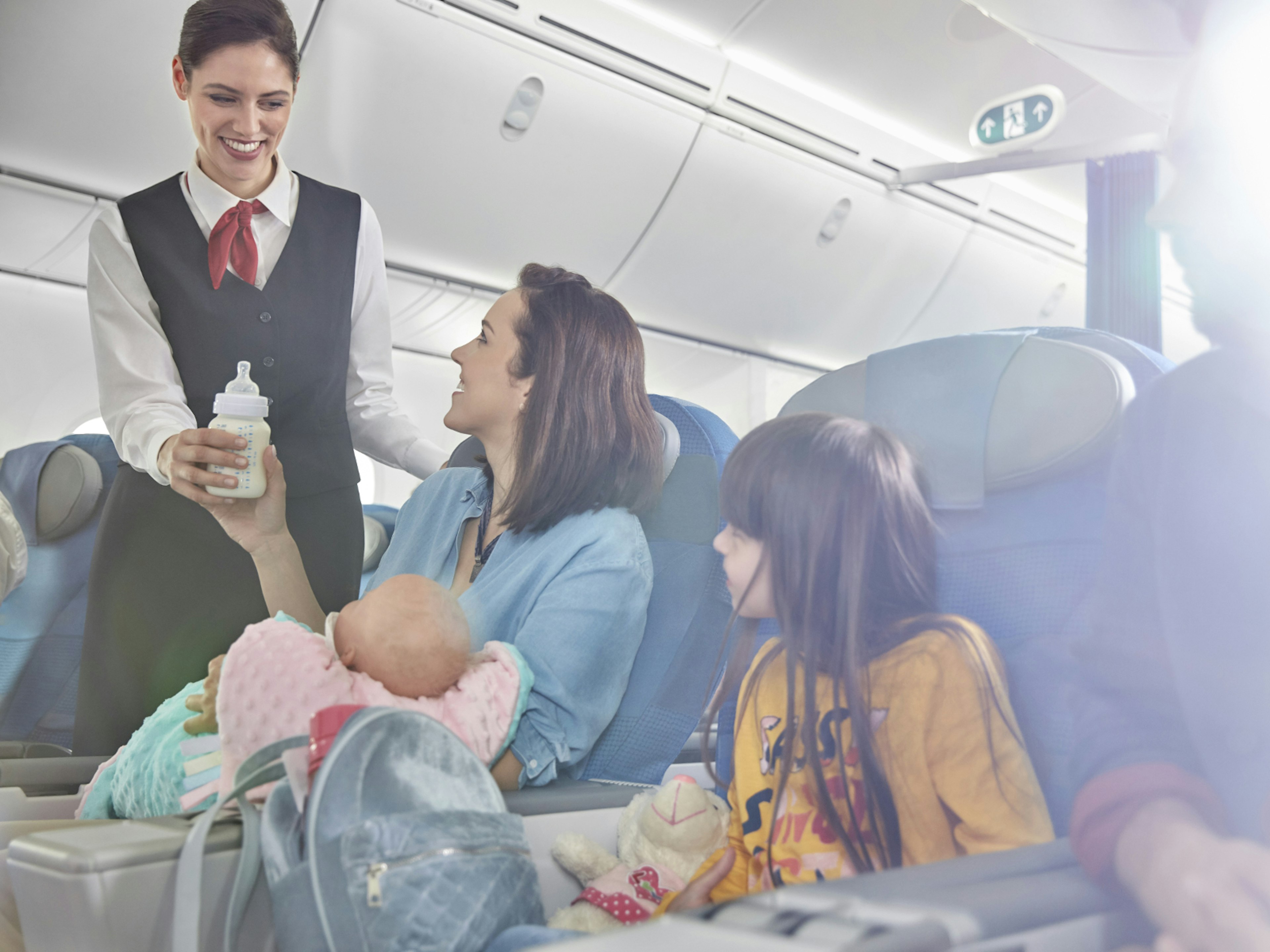 A flight attendant handing a mother her baby bottle