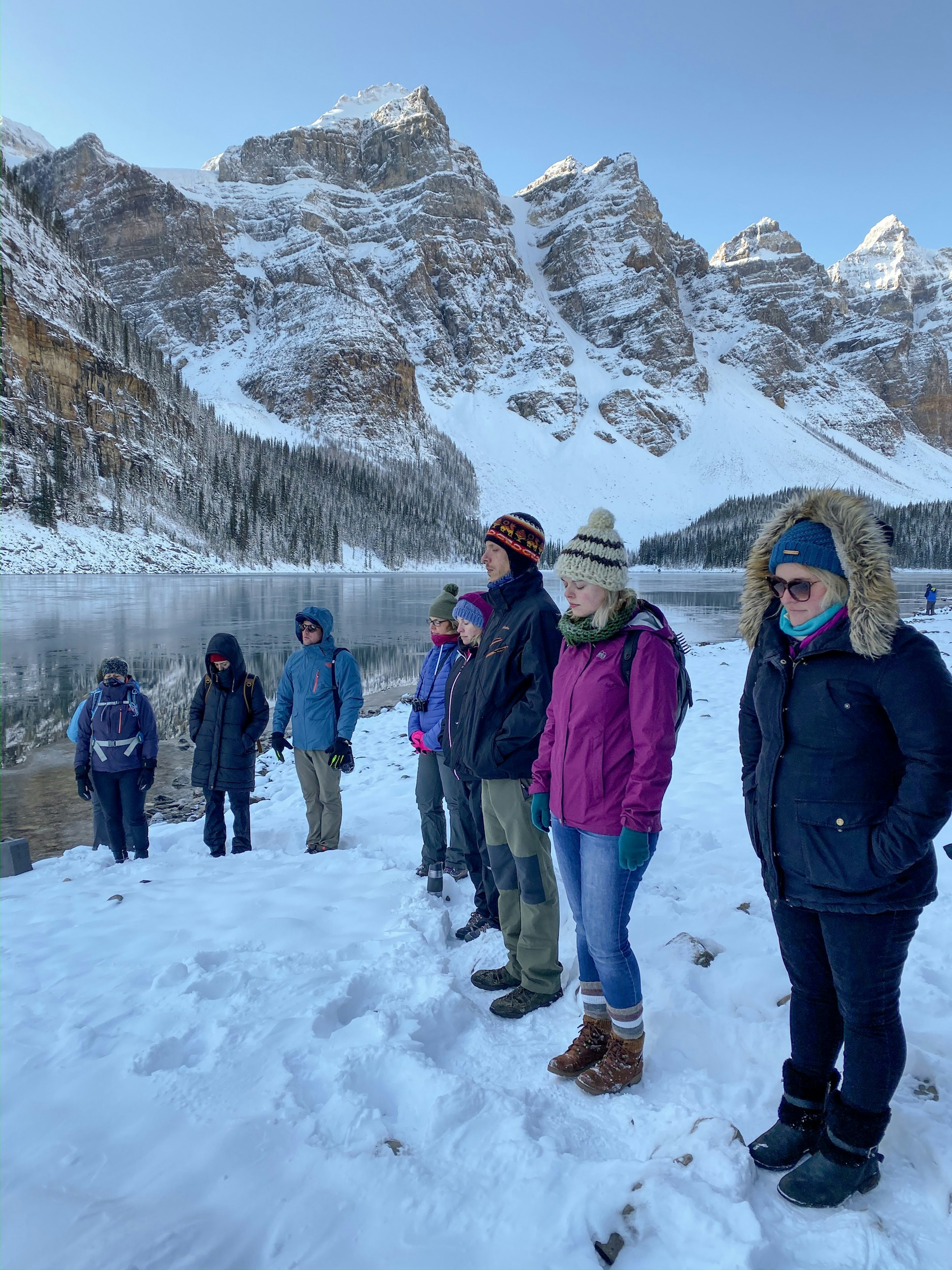 People meditate on the edge of Moraine Lake in deep snow during winter at Banff and Lake Louise