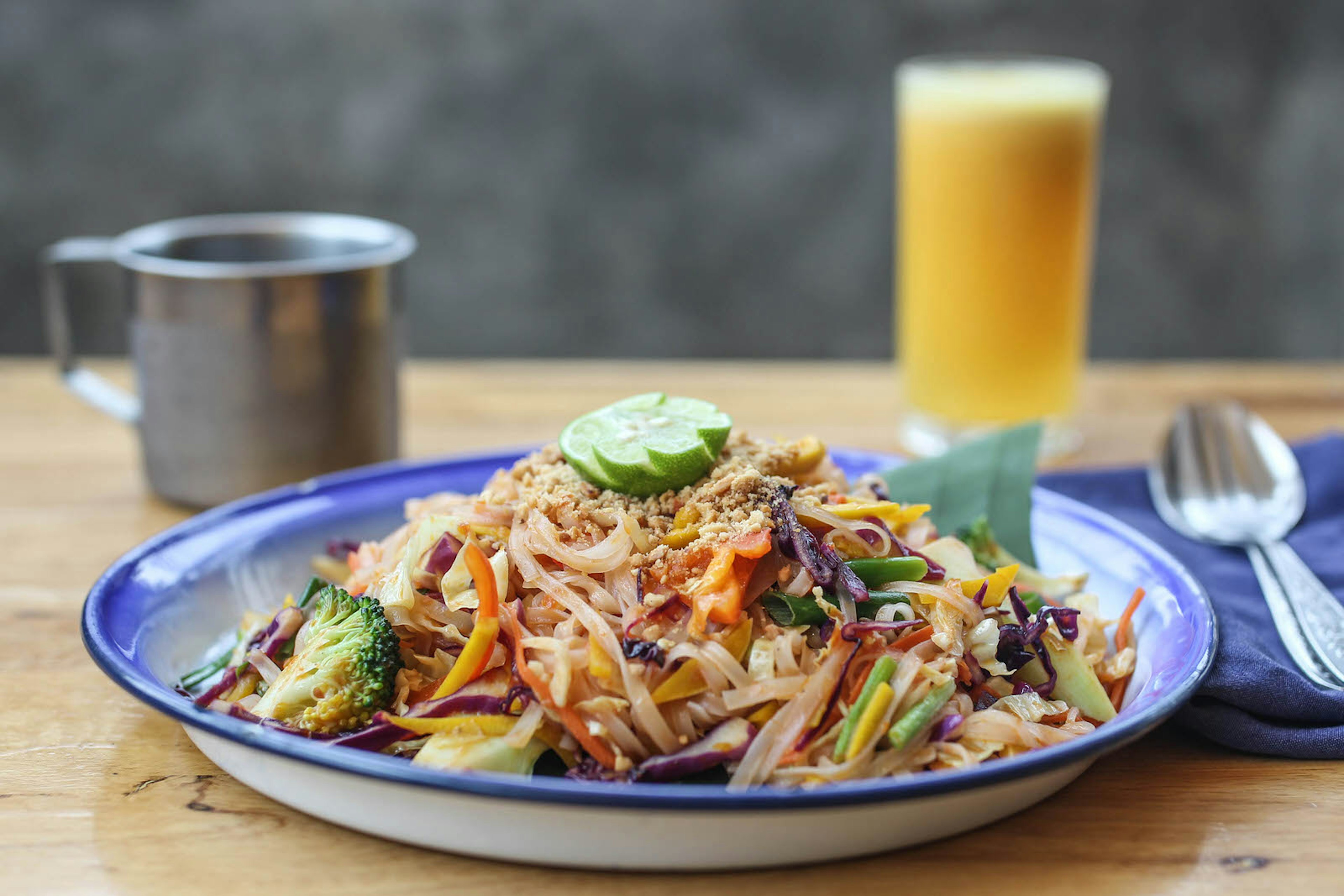 A vibrant dish of vegetarian pad thai and fresh orange juice served at Free Bird Cafe