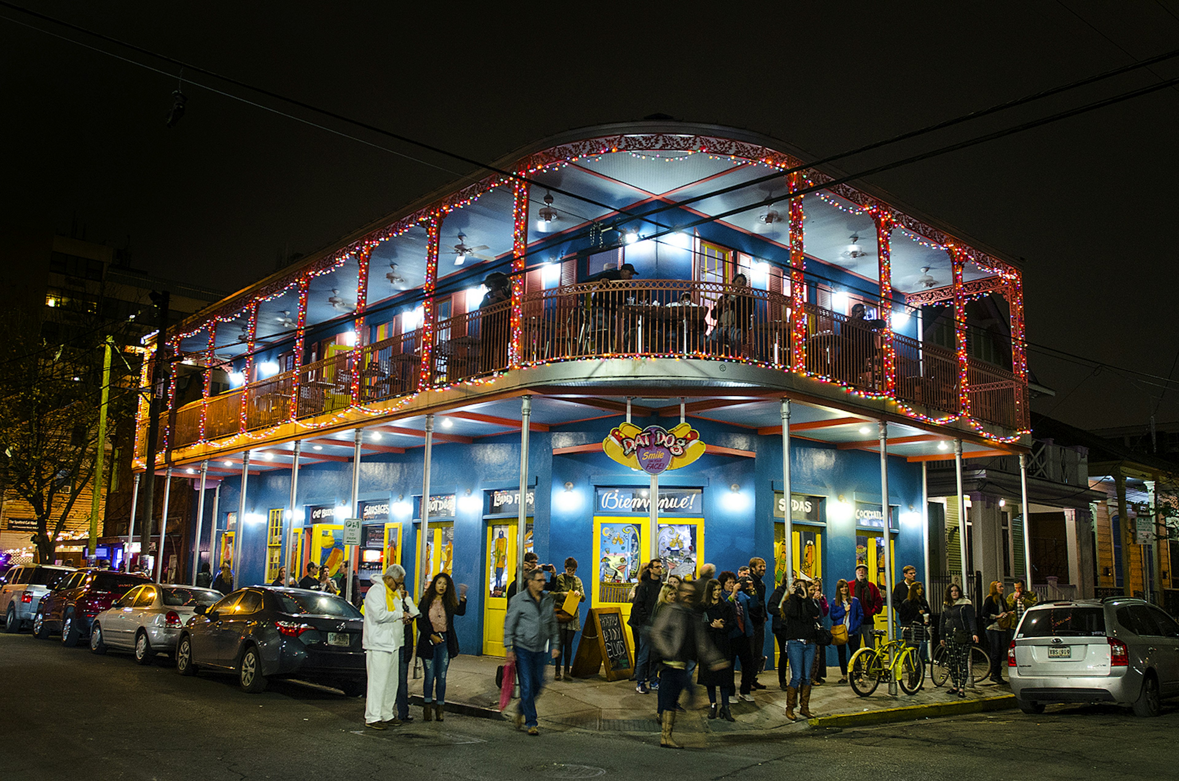 Two-story 19th-century building in New Orleans with wrought-iron railings is illuminated at night