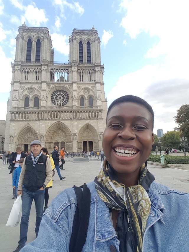 A black woman smiles in front of the cathedral of Notre Dame in Paris