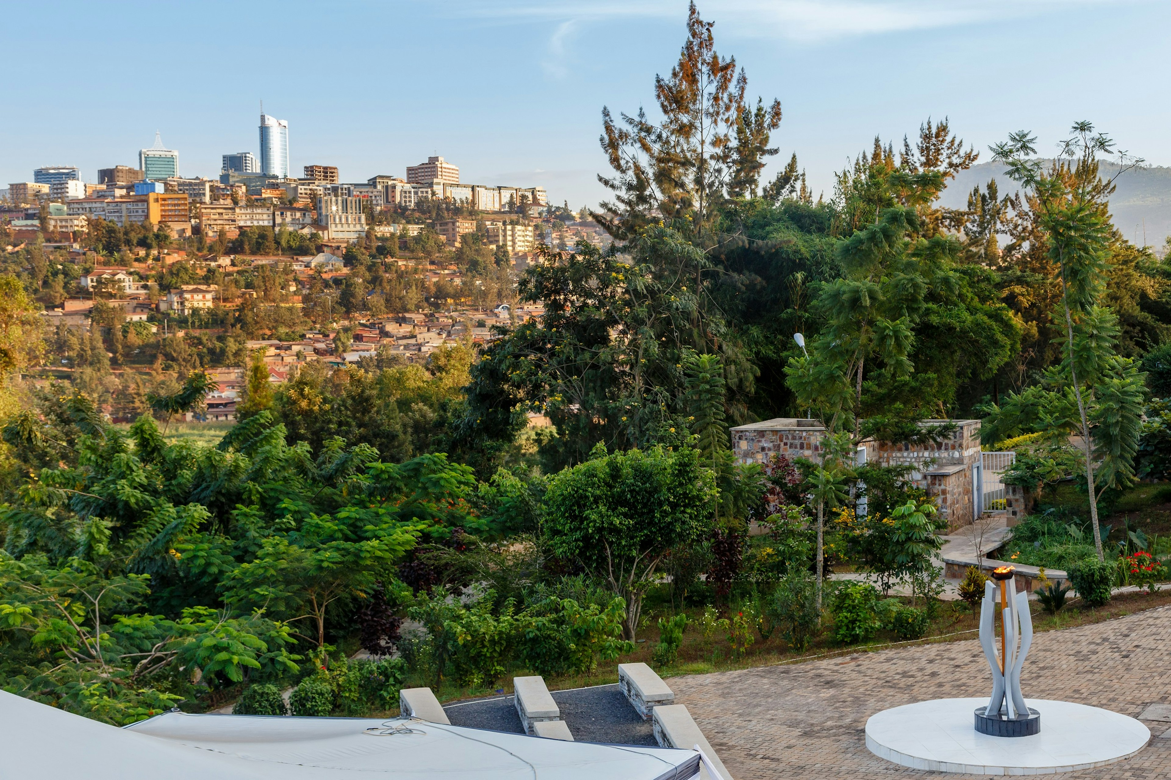 A memorial flame is lit in the foreground, with a cityscape stretching out in the distance.