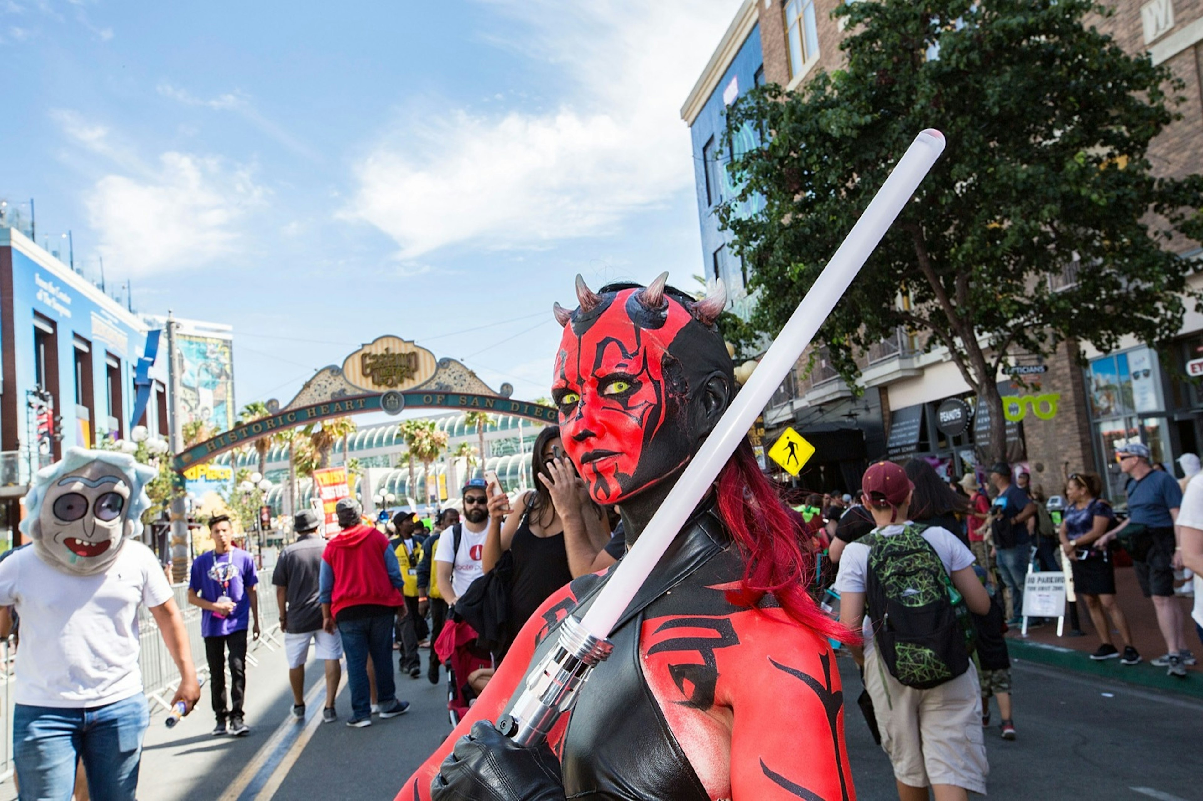 woman dressed as a black red Darth Maul Sith with her light saber under the Gas Lamp sign