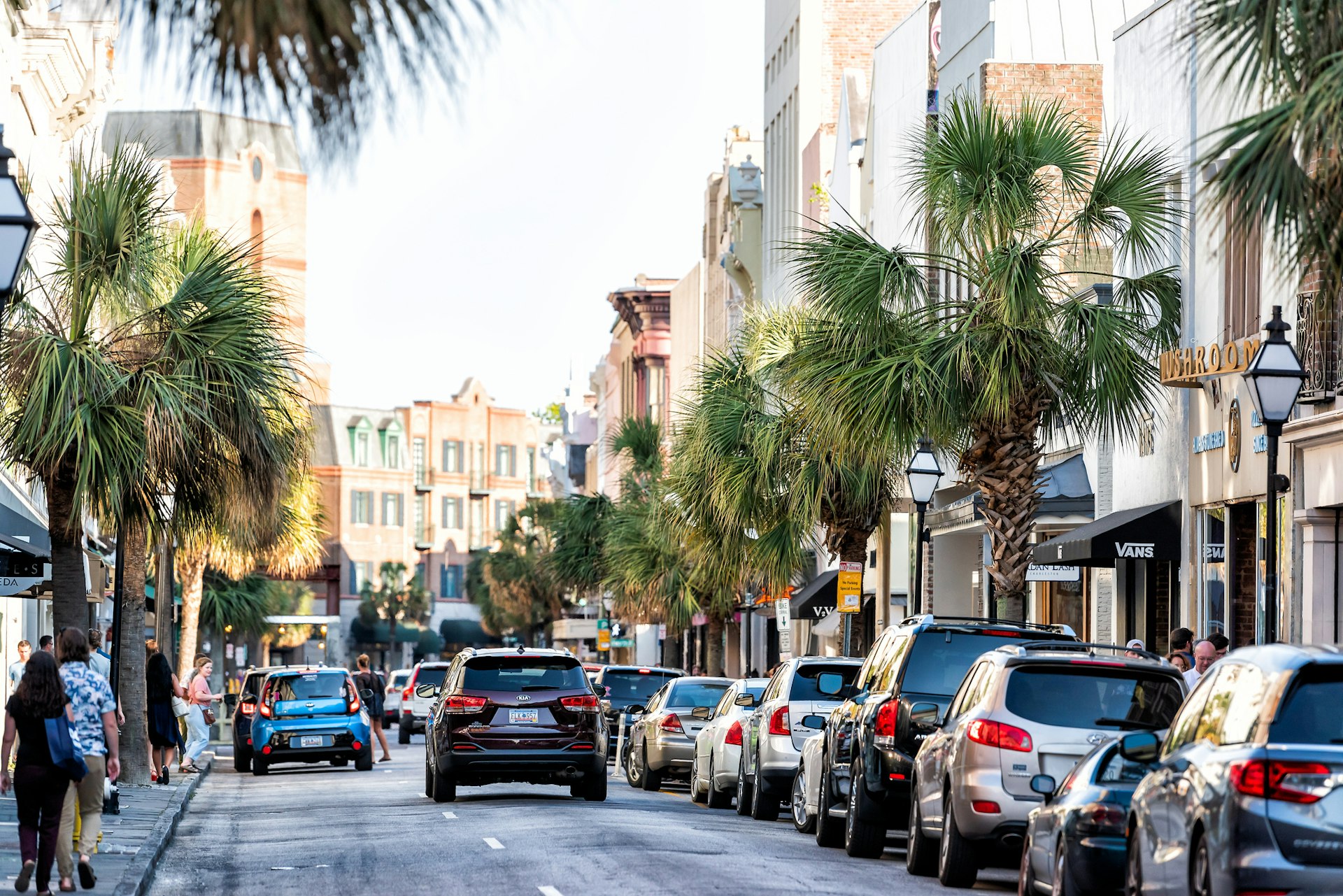  Downtown city King street in South Carolina with people walking in southern town at sunset by shops, restaurants, cars parked on road