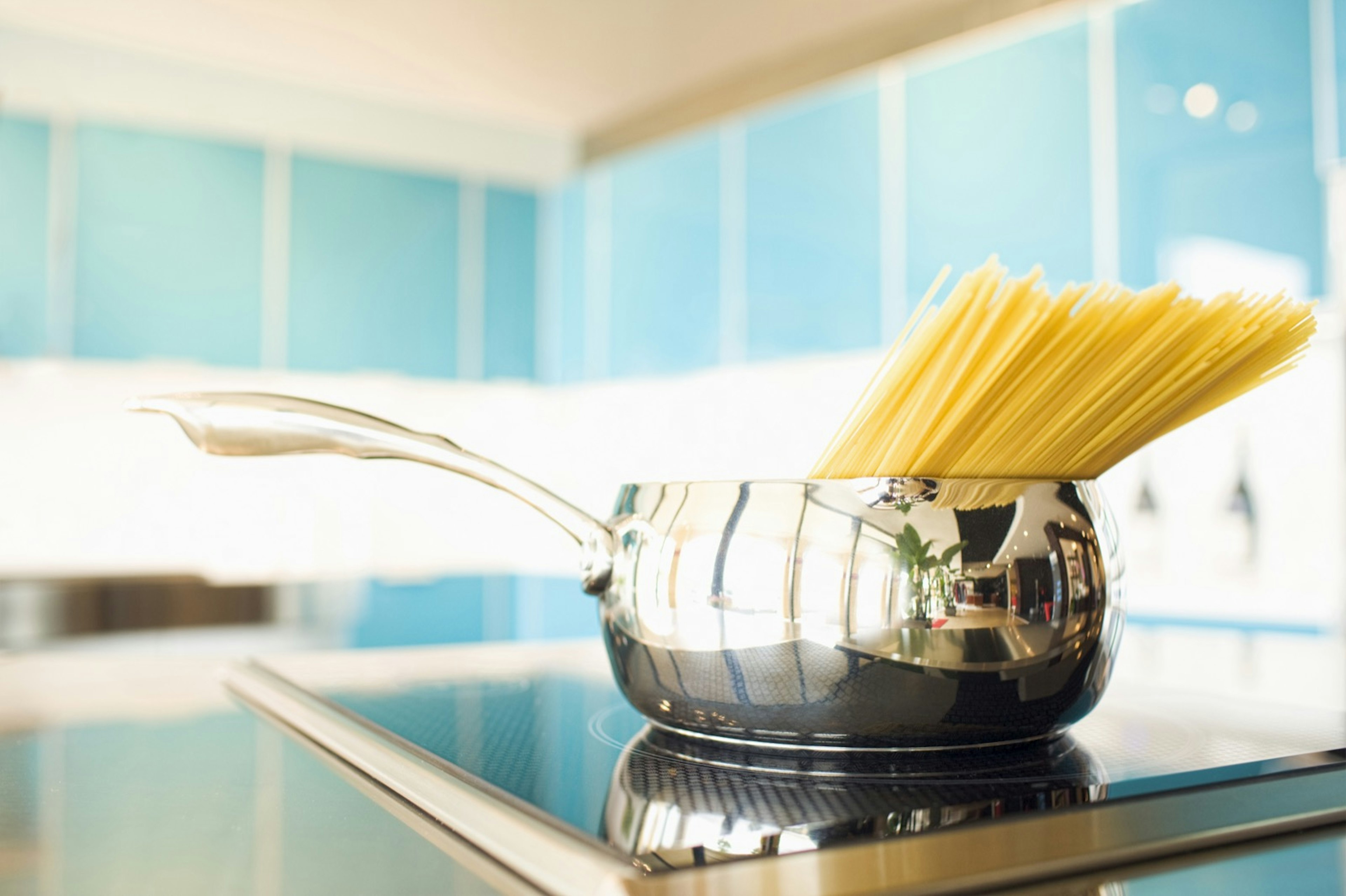 Pasta sticking out of a chrome pot over a stove; easy hostel meals