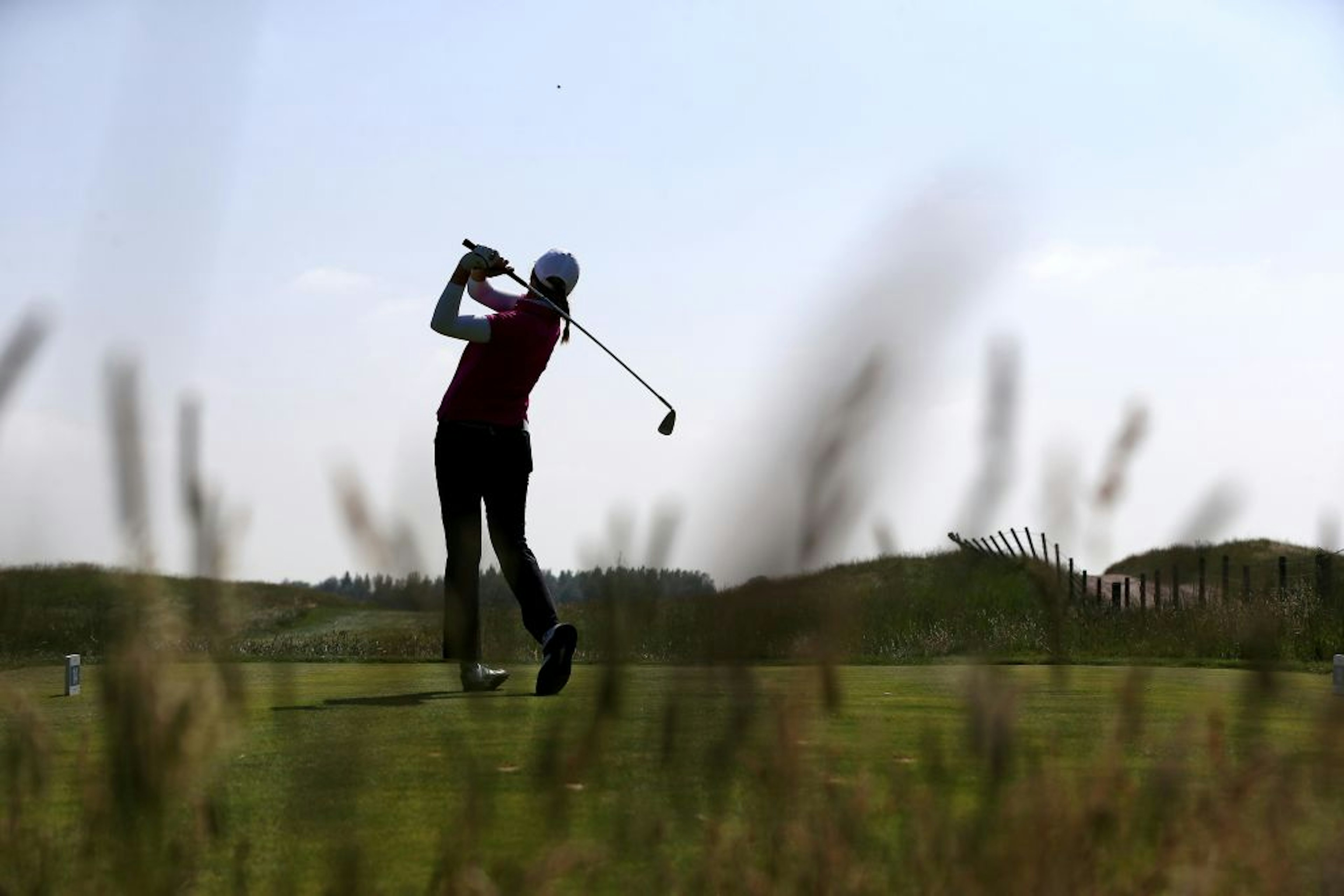 Image shot through the weeds of a woman post-swing