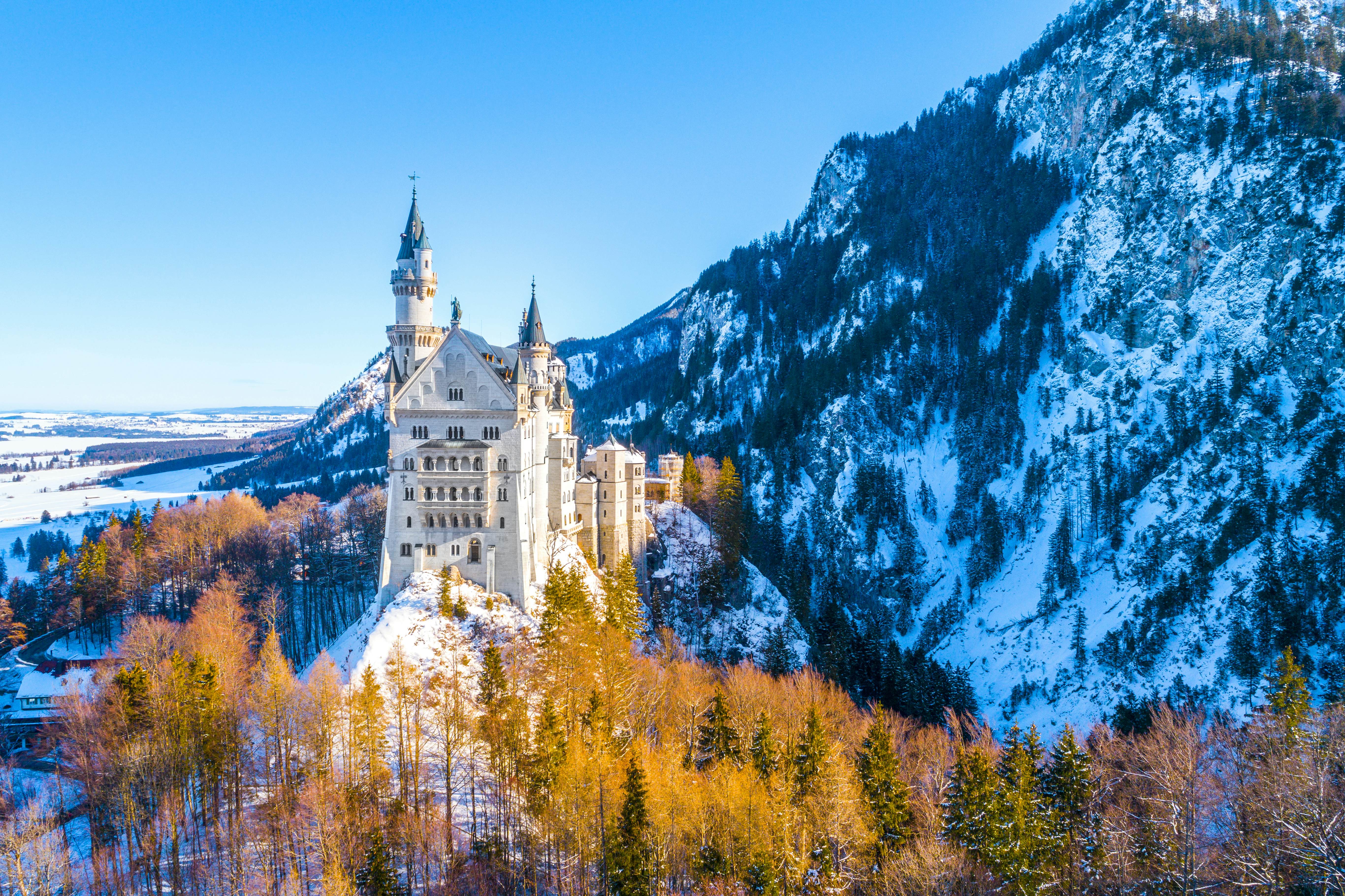 View of Neuschwanstein Castle framed by snowy mountains in Bavaria, Germany.