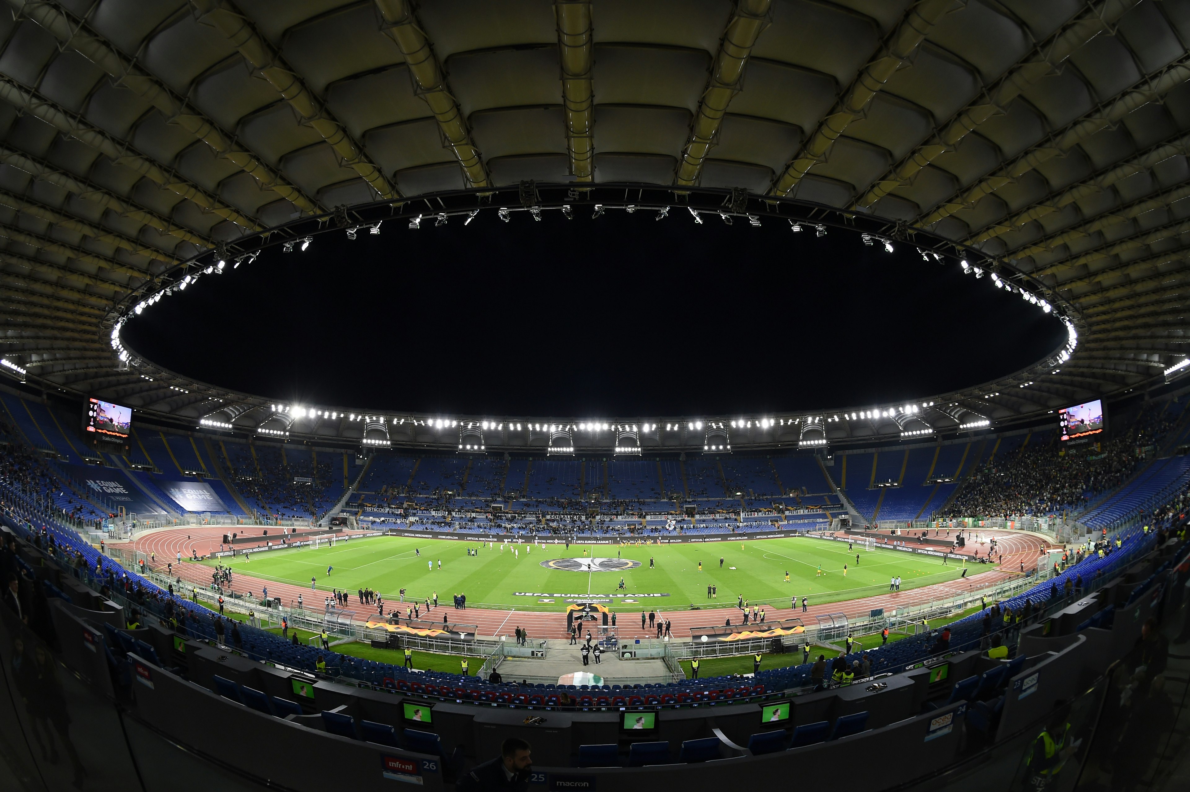 A fish-eye view of the inside of Rome's Stadio Olympico; the football pitch is floodlit and there is a game underway