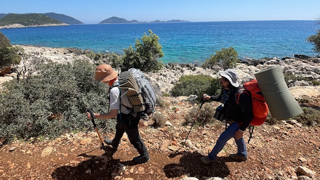 Tourists walk along long-distance hiking trail on the margin of sea at Lycian Way in Antalya, Türkiye