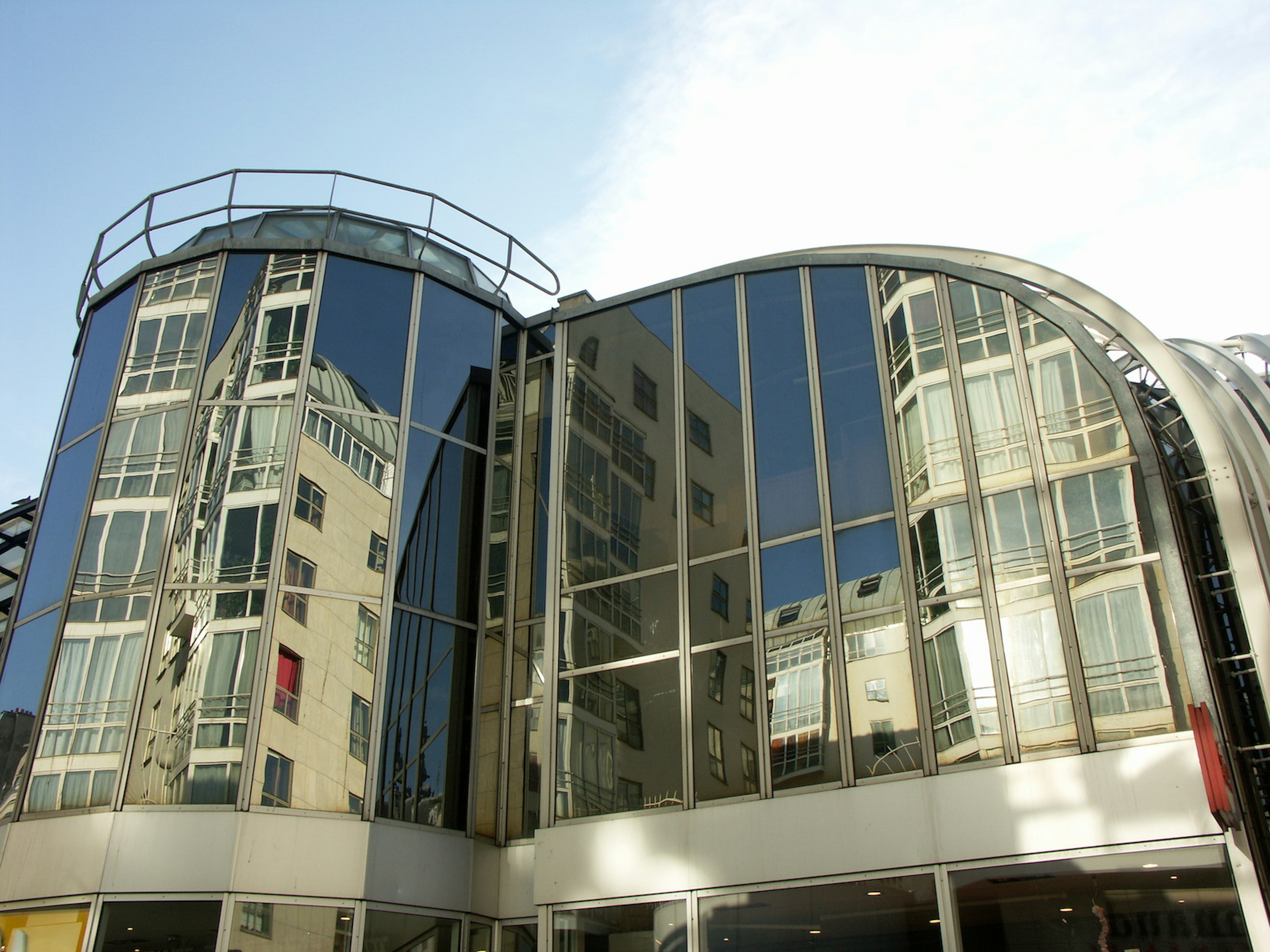 Les Halles forum- a glass building with reflections in the windows of its neighbors across the street