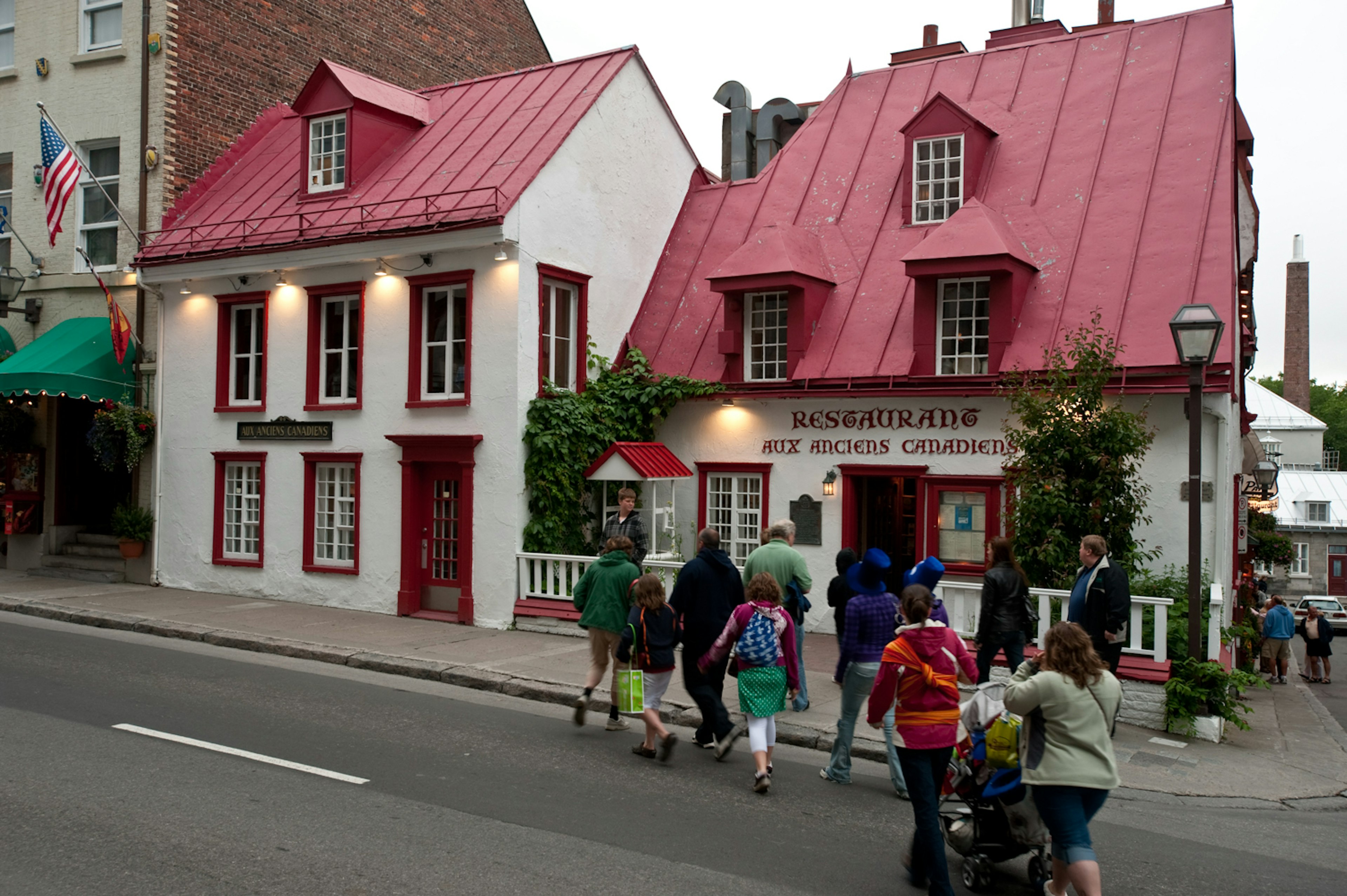 Aux Anciens Canadiens old-fashioned restaurant. A group of walkers are crossing the road to get to the restaurant.