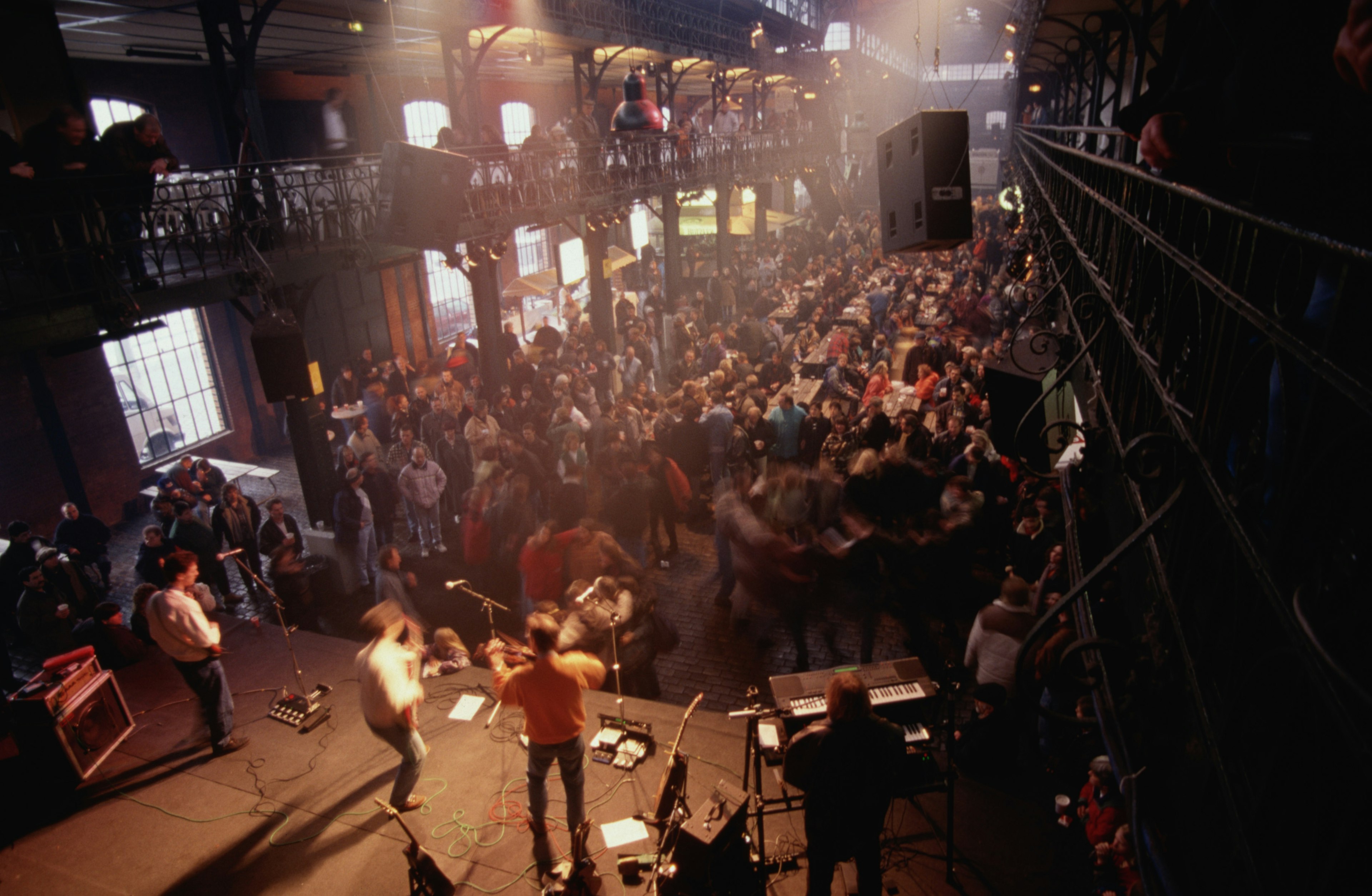 A band plays on a small stage in front of an active audience