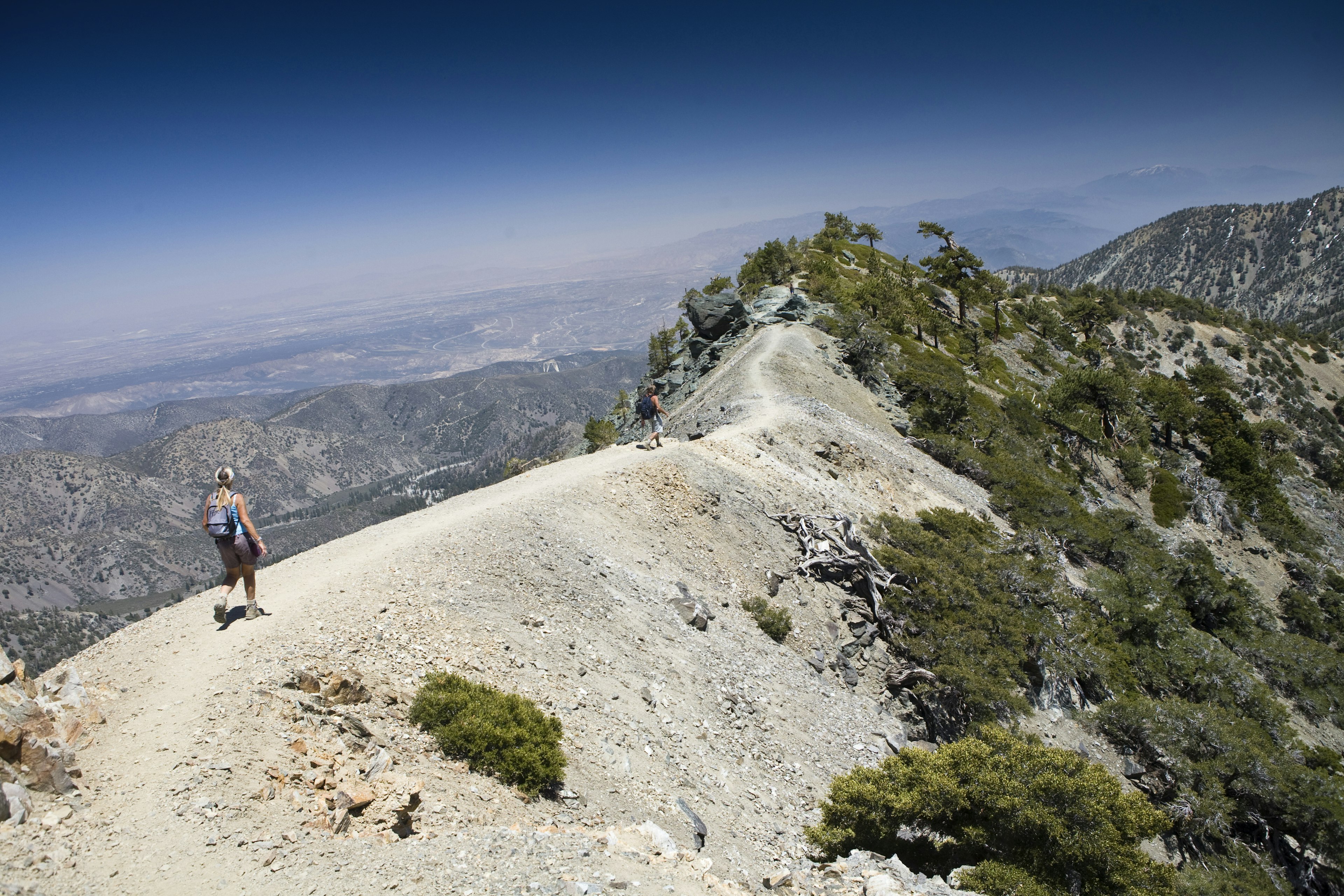 Two people hike the spine of a mountain range