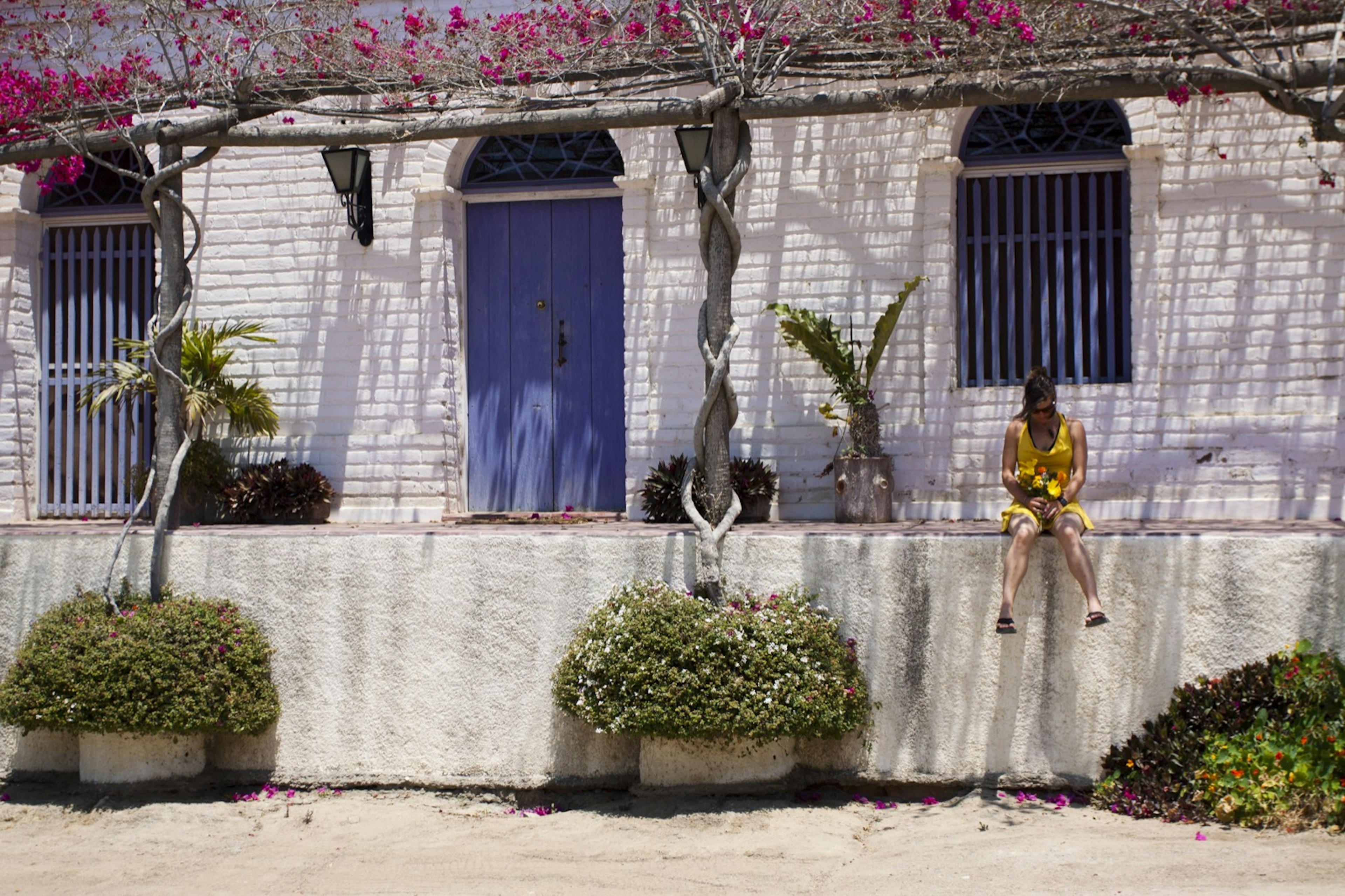 A woman sits in on the edge of a blue and white buildilng