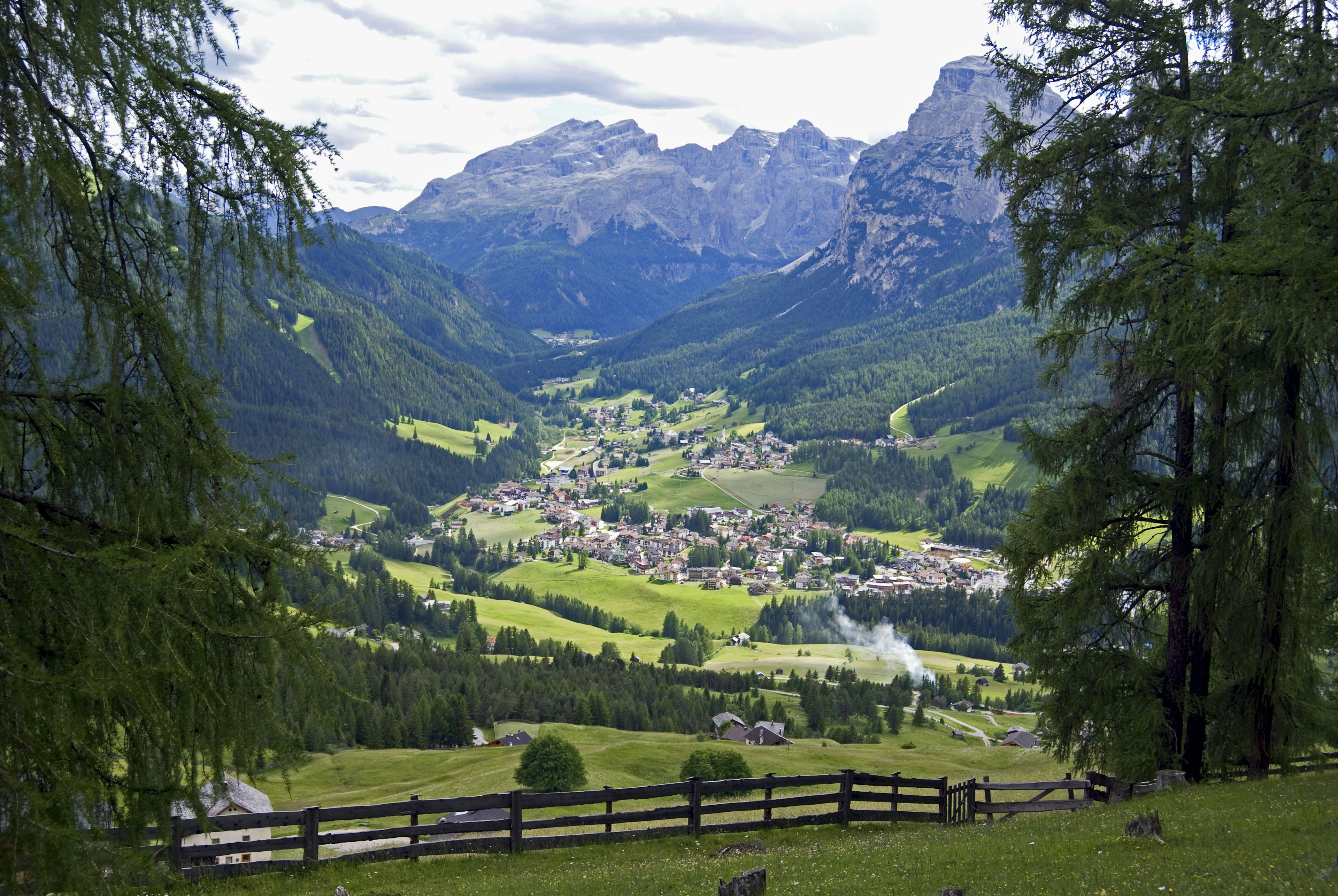 A view over La Villa, a settlement in a green valley with a mountainous Dolomites backdrop.