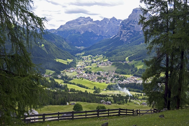 A view over La Villa, a settlement in a green valley with a mountainous Dolomites backdrop.