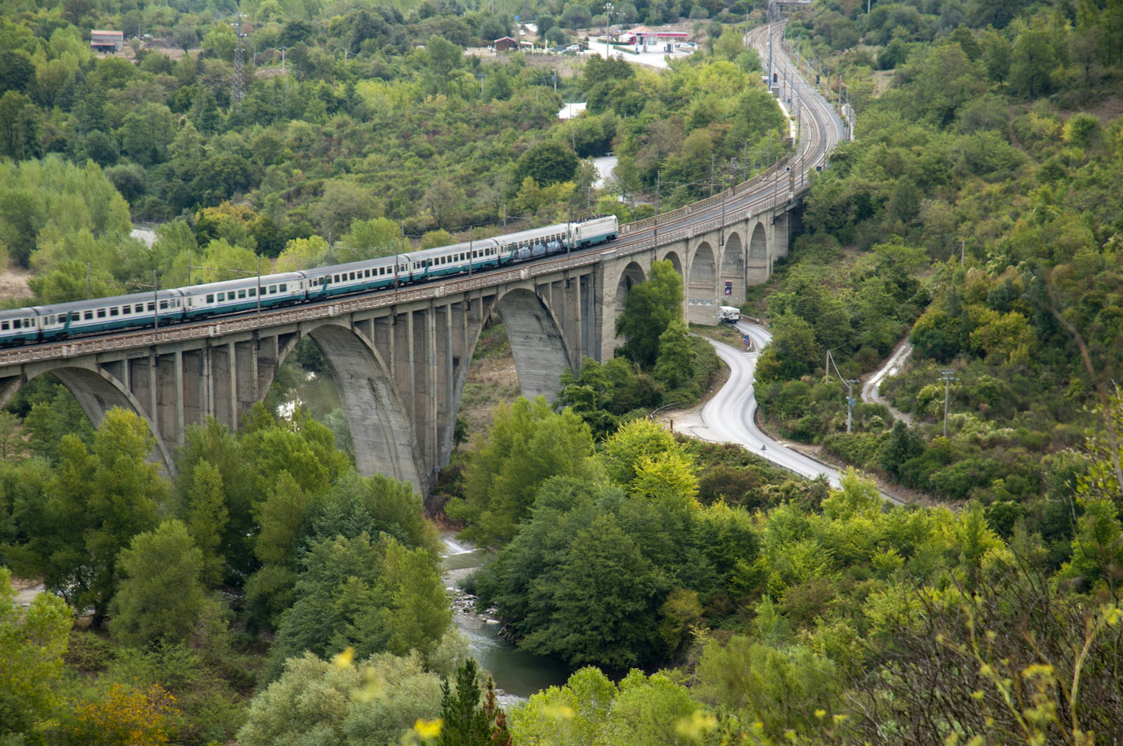 A train crossing over a multi-arched bridge through a rural area