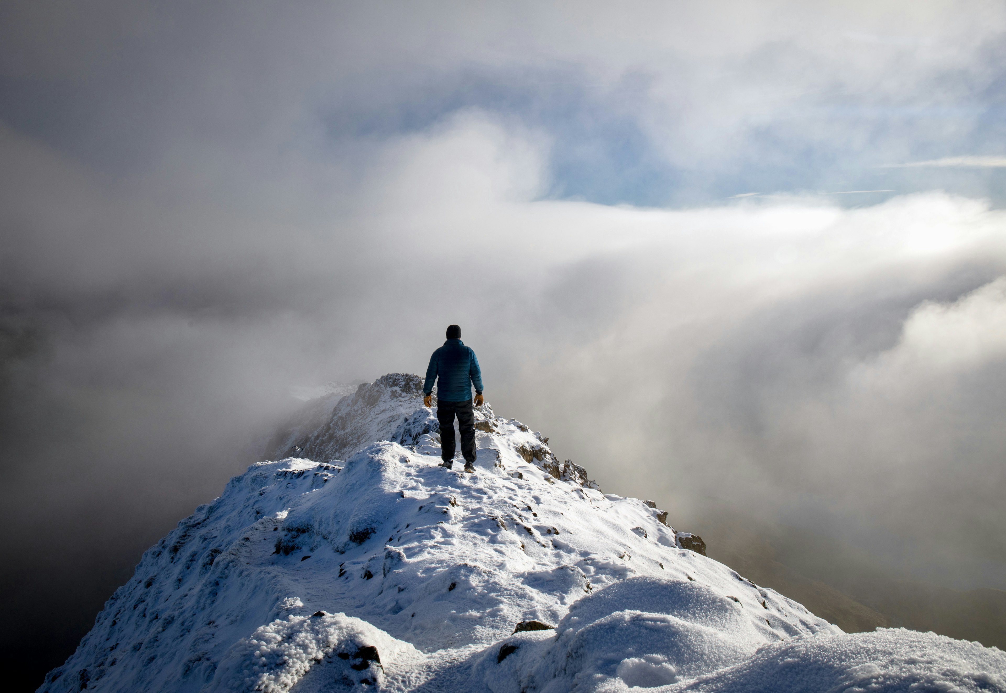 A solo hiker above the clouds at the peak of Snowdonia, Wales, United Kingdom