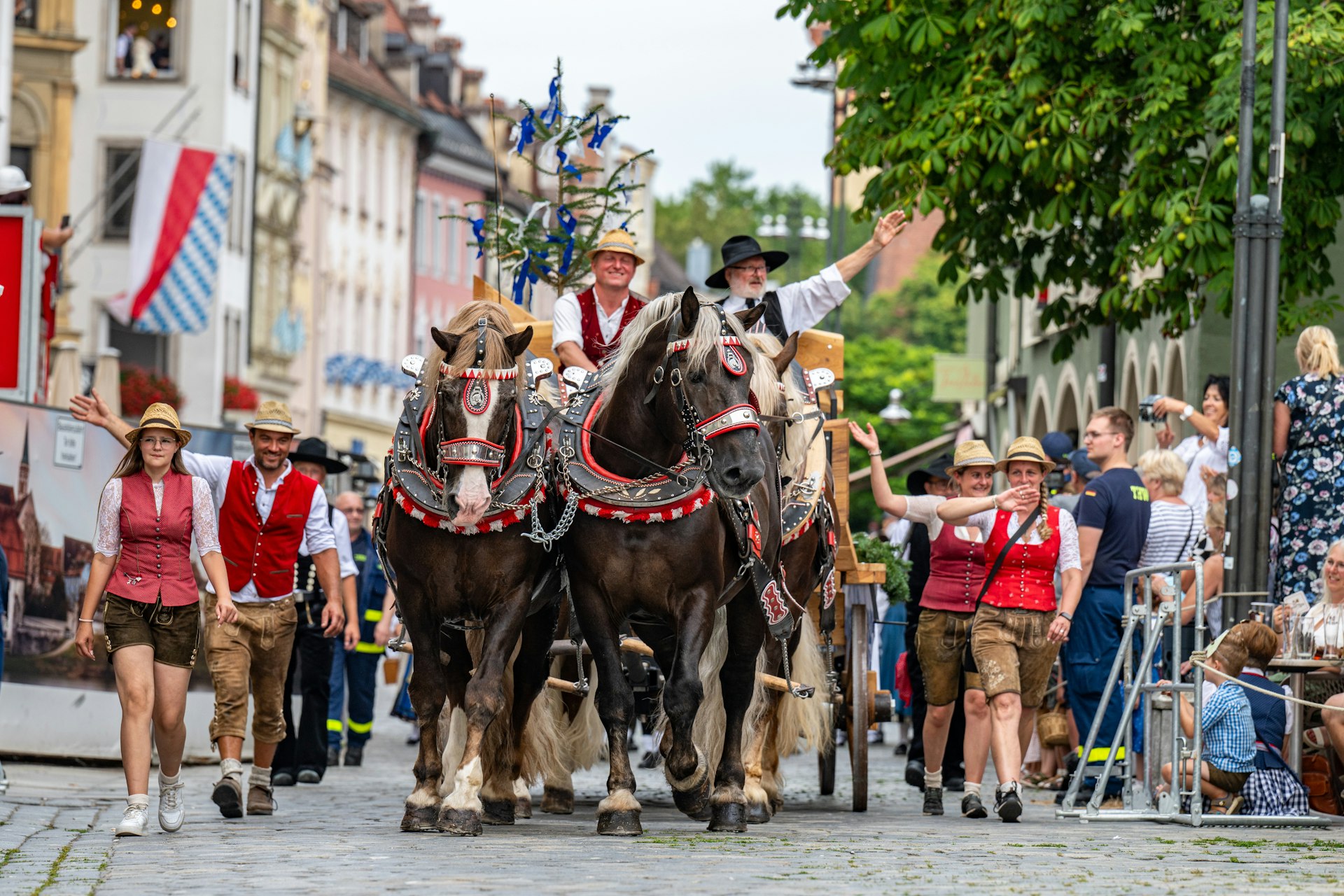 Participants in traditional Bavarian dress, one mounted on horseback, walk through the city cetner to kick off the Gäubodenvolksfest festival, Staubing, Germany