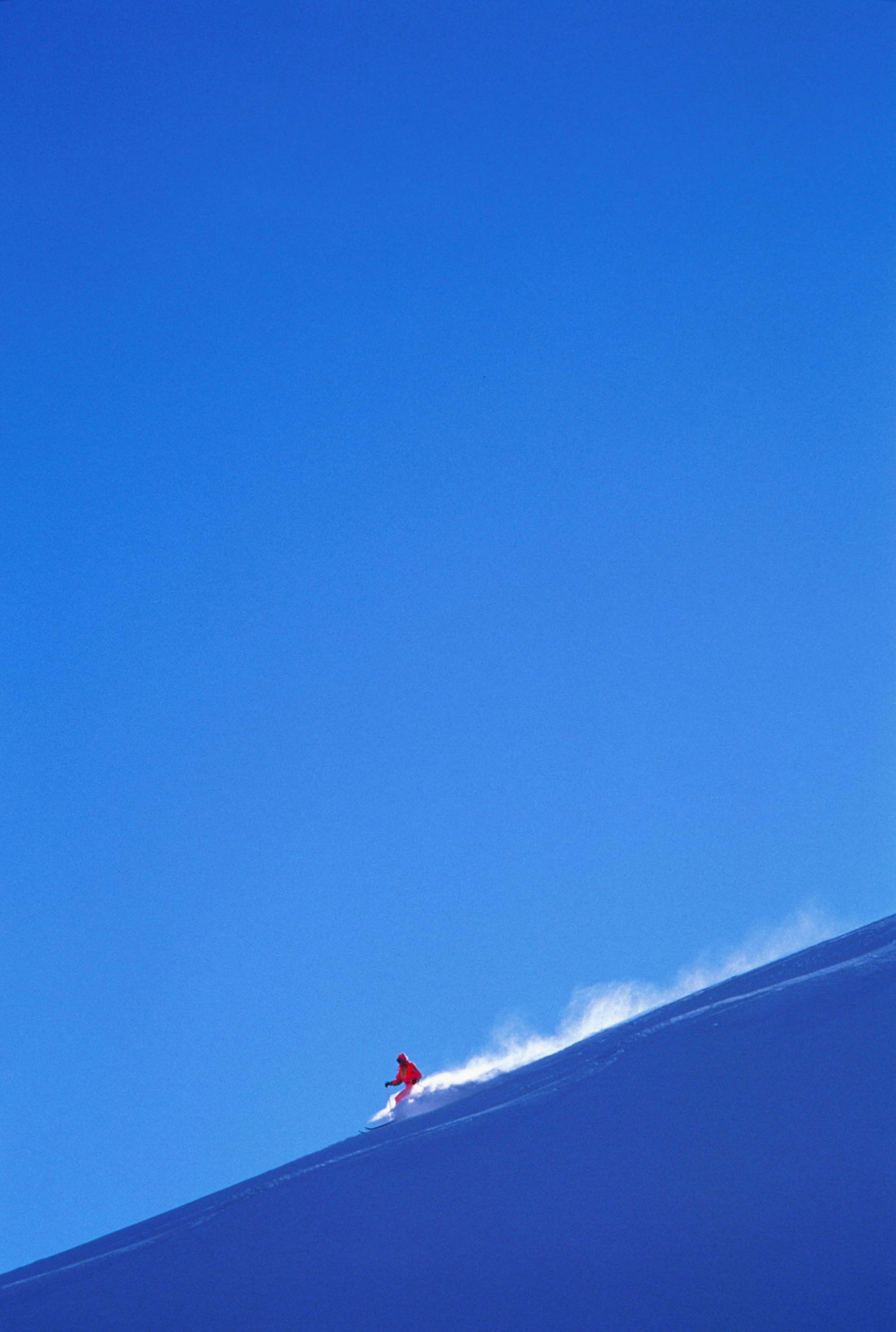 Skier kicks up powder against a blue sky