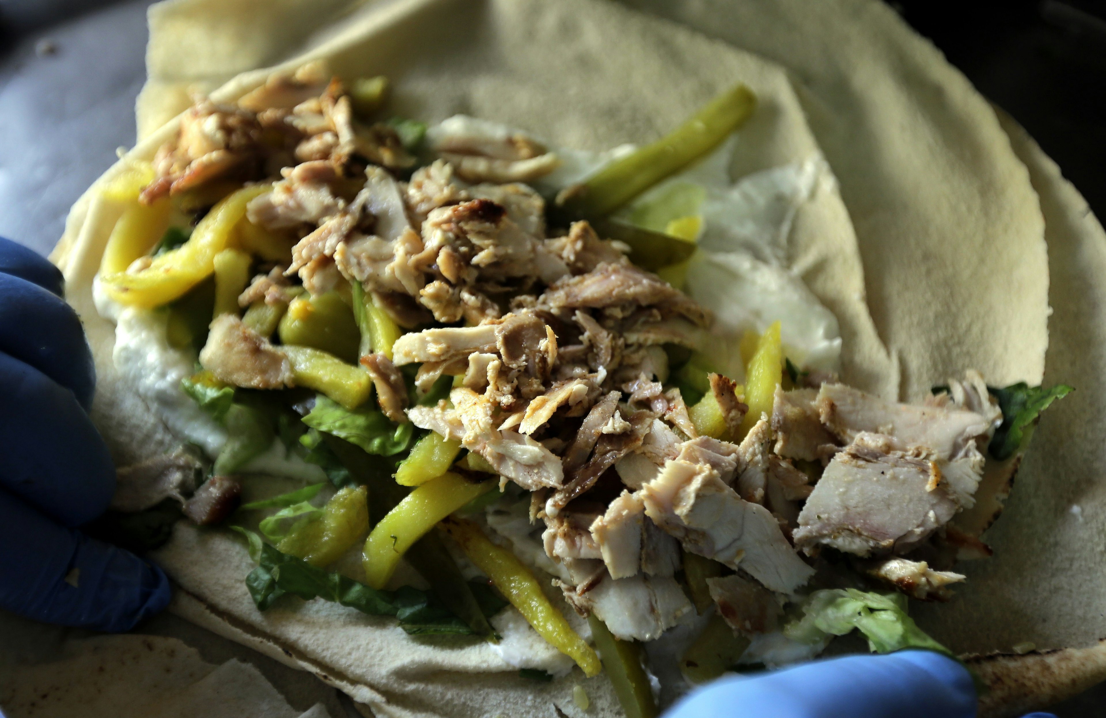 Lebanese chicken shawarma is rolled up before toasting