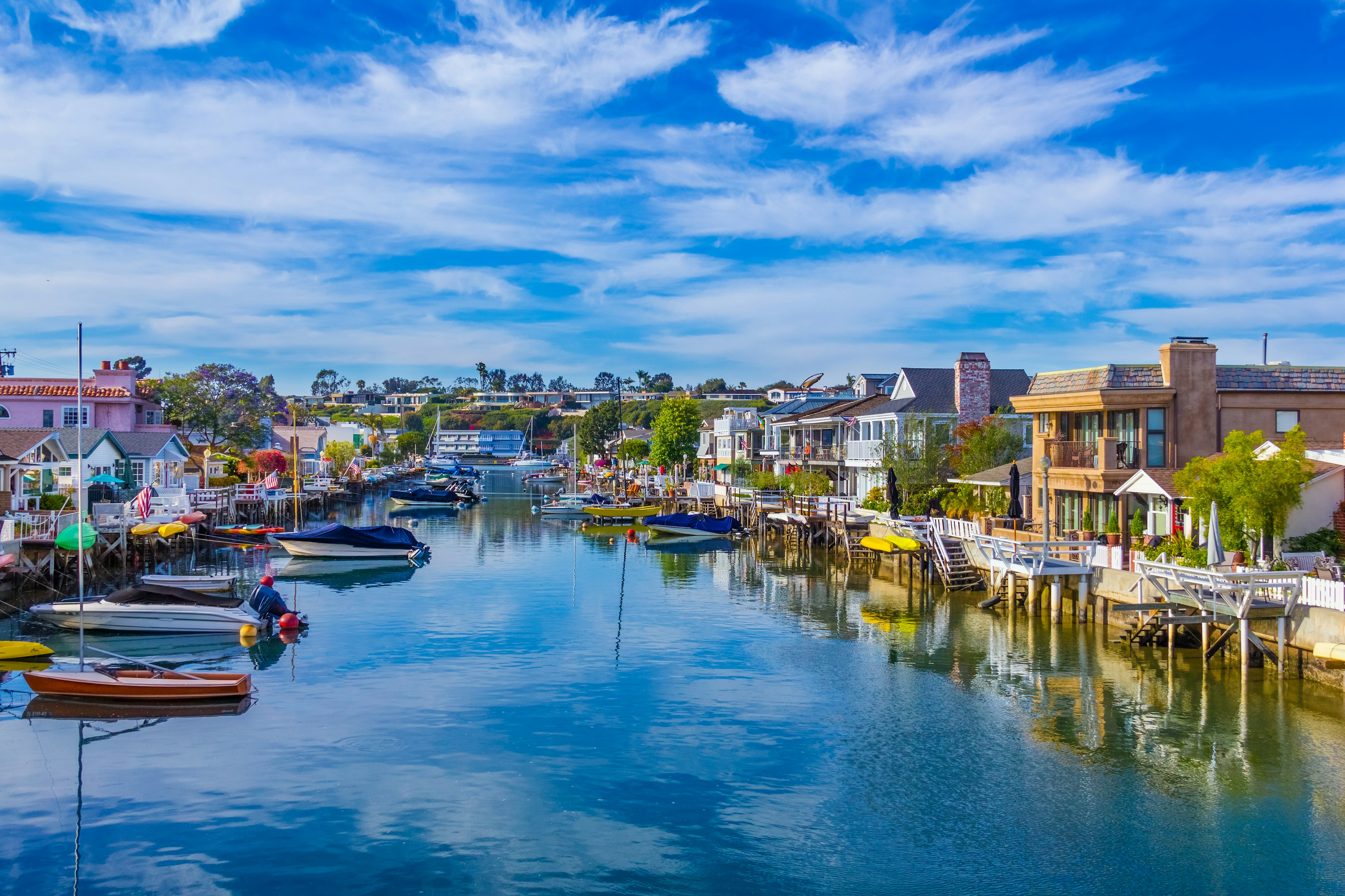 a canal between rows of colorful houses lined with boats