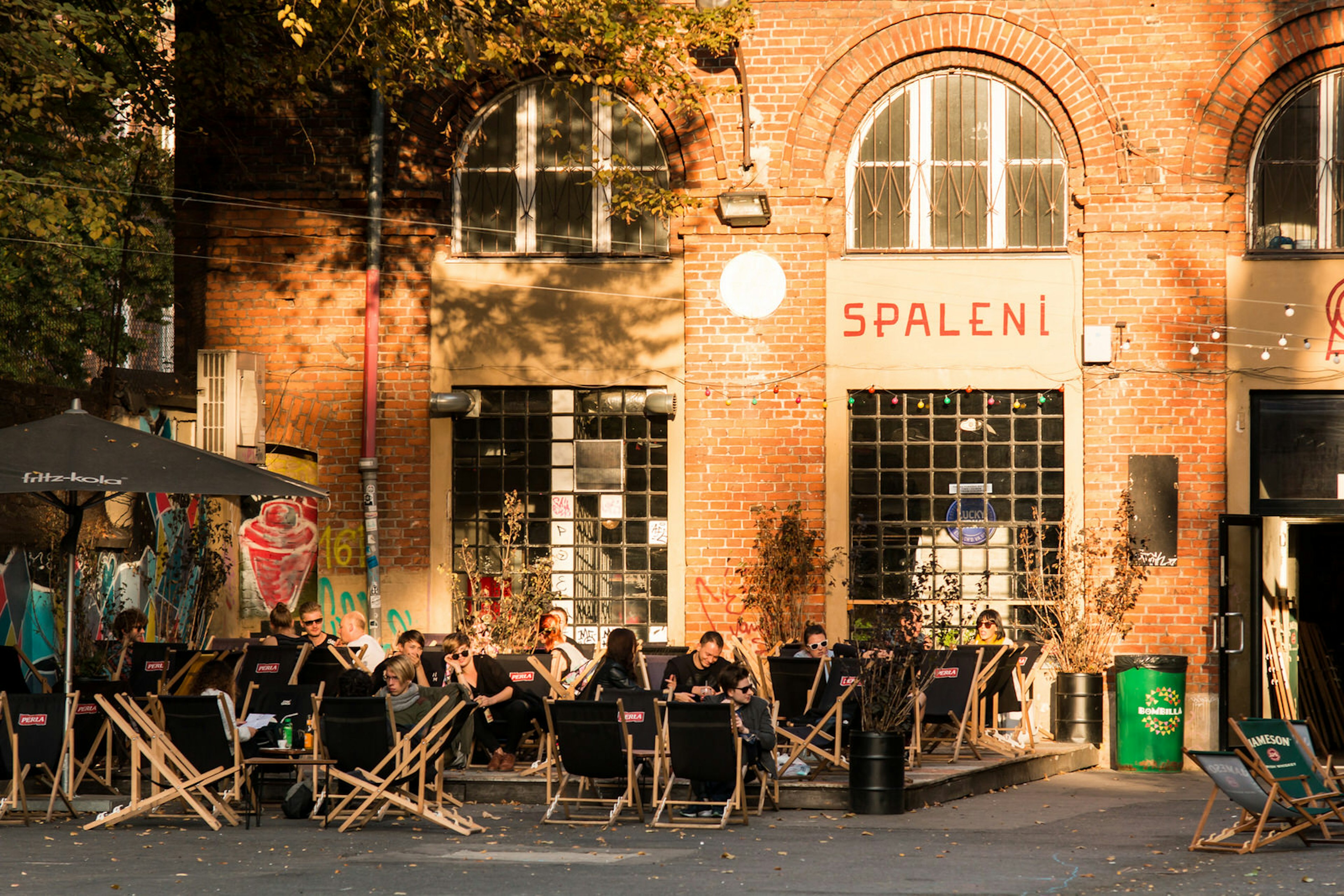 Bar-goers enjoying drinks on deck chairs outside trendy Spaleni Słońcem, a cocktail bar in OFF Piotrkowska © Michal Ludwiczak / Getty Images