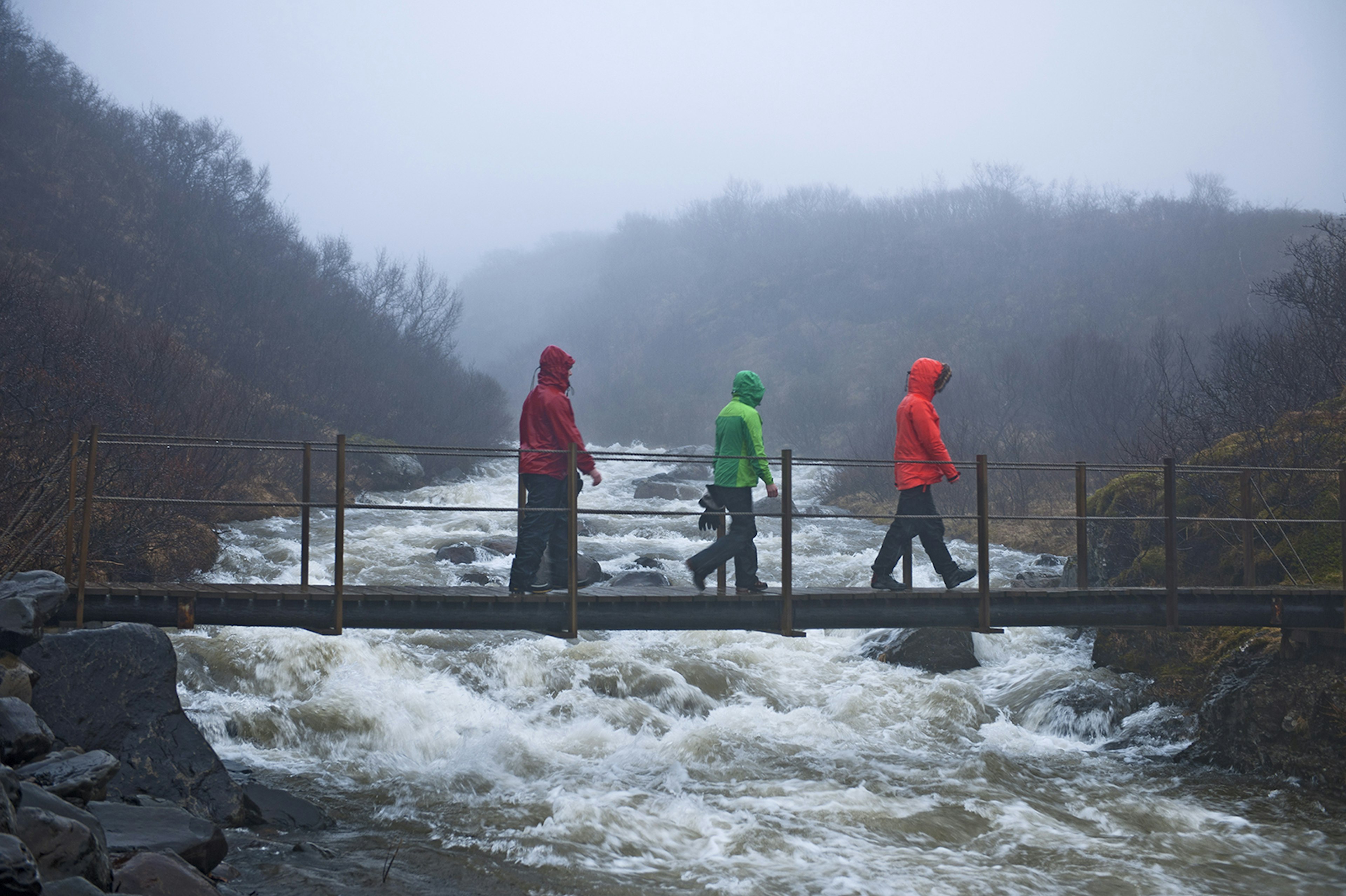 Group of hikers crossing foot bridge in rain, Skaftafell, Vatnajokull National Park, Iceland © Henn Photography / Getty Images