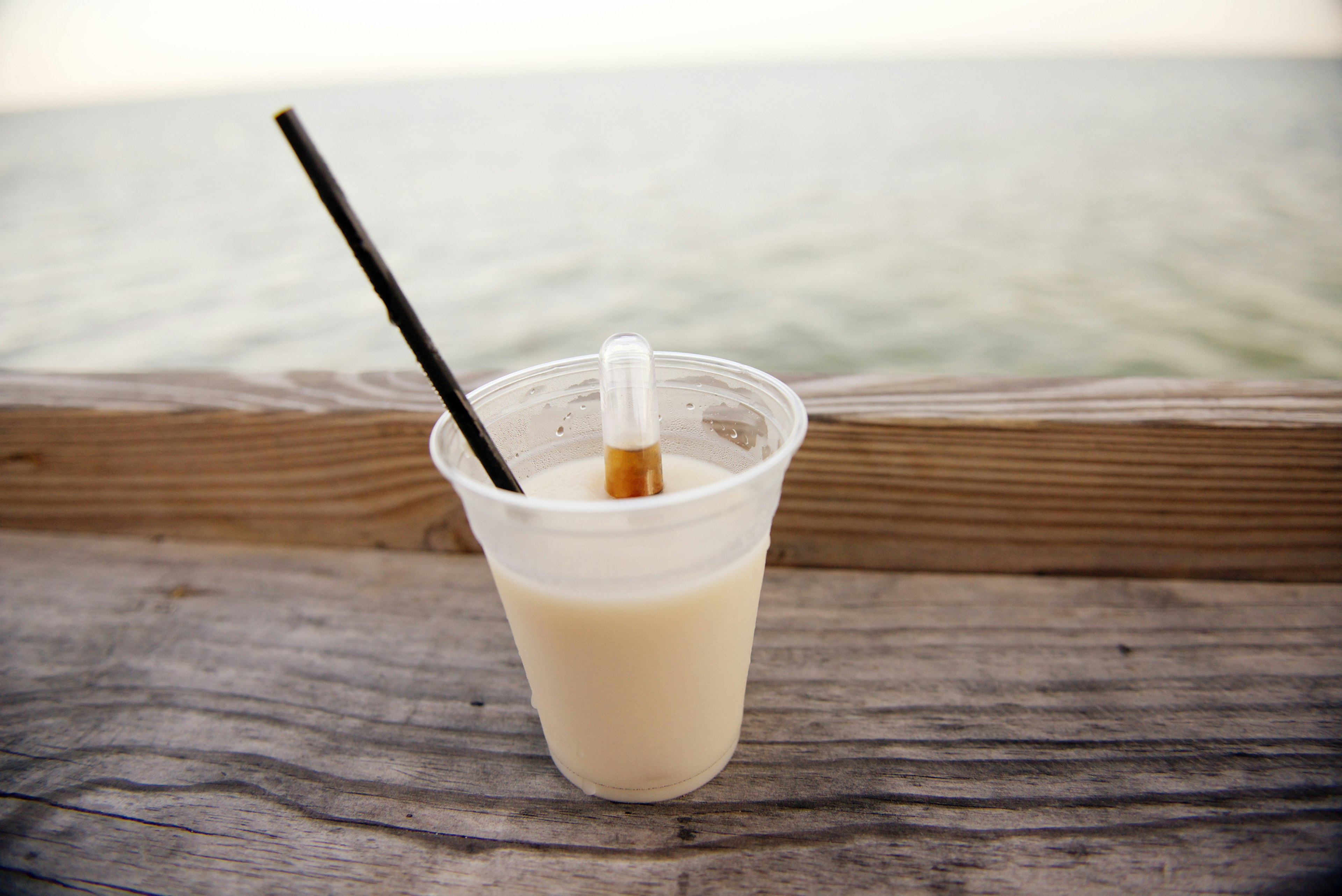 Rum runner cocktail set on a wooden railing over the sand