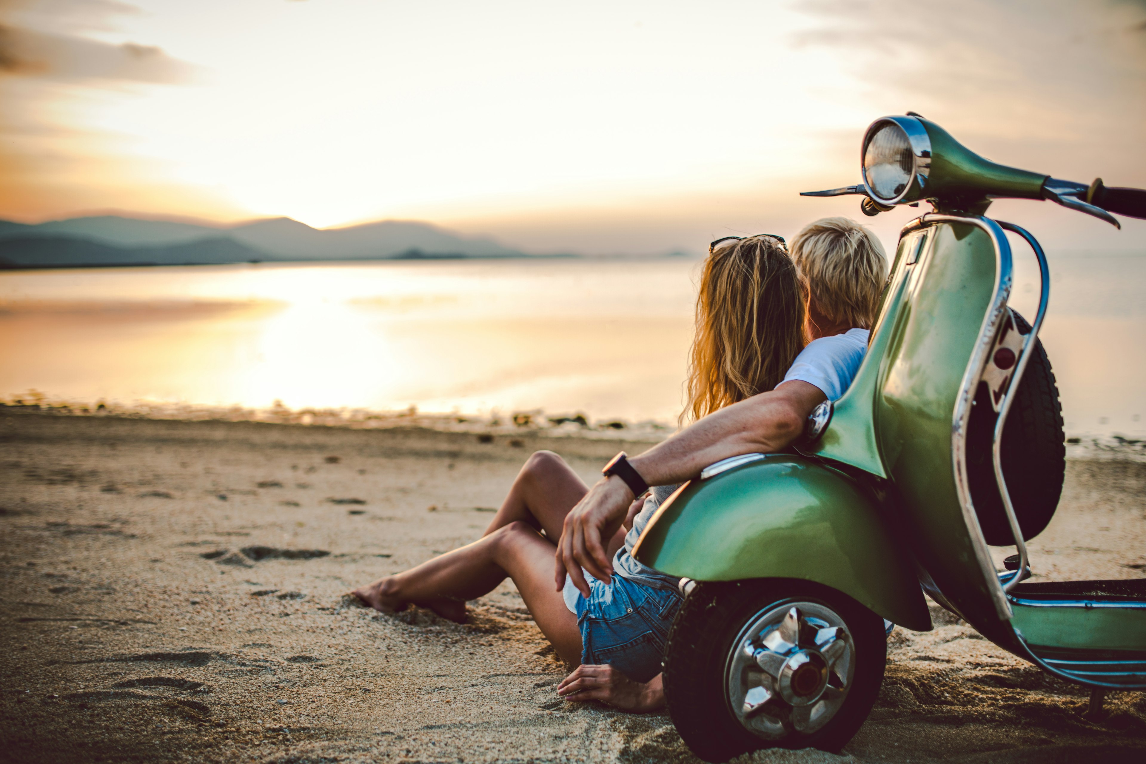 Romantic couple with retro bike on vacation watching sunset