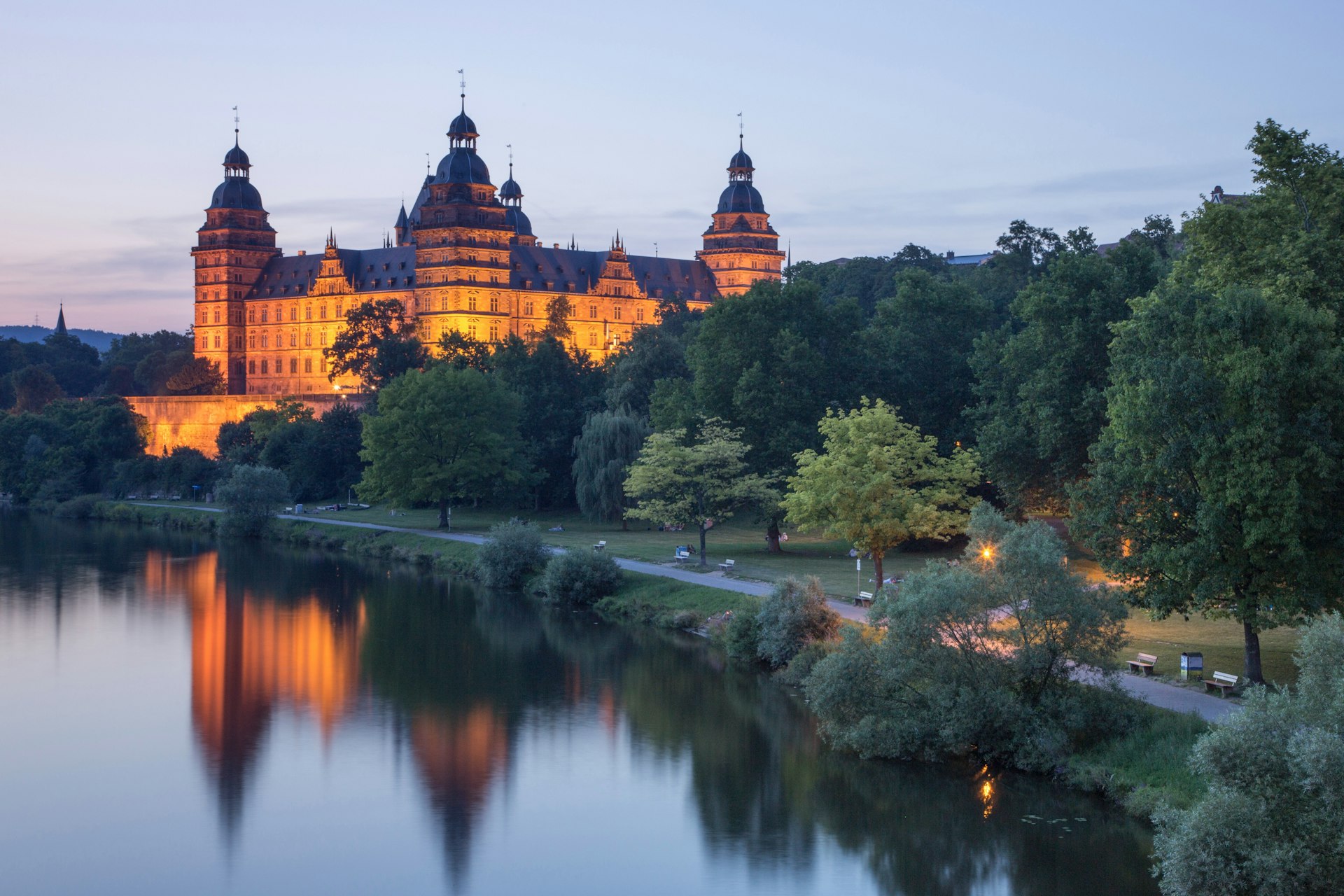 Schloss Johannisburg Palace and parklands along Main river at dusk, Bavaria, Germany