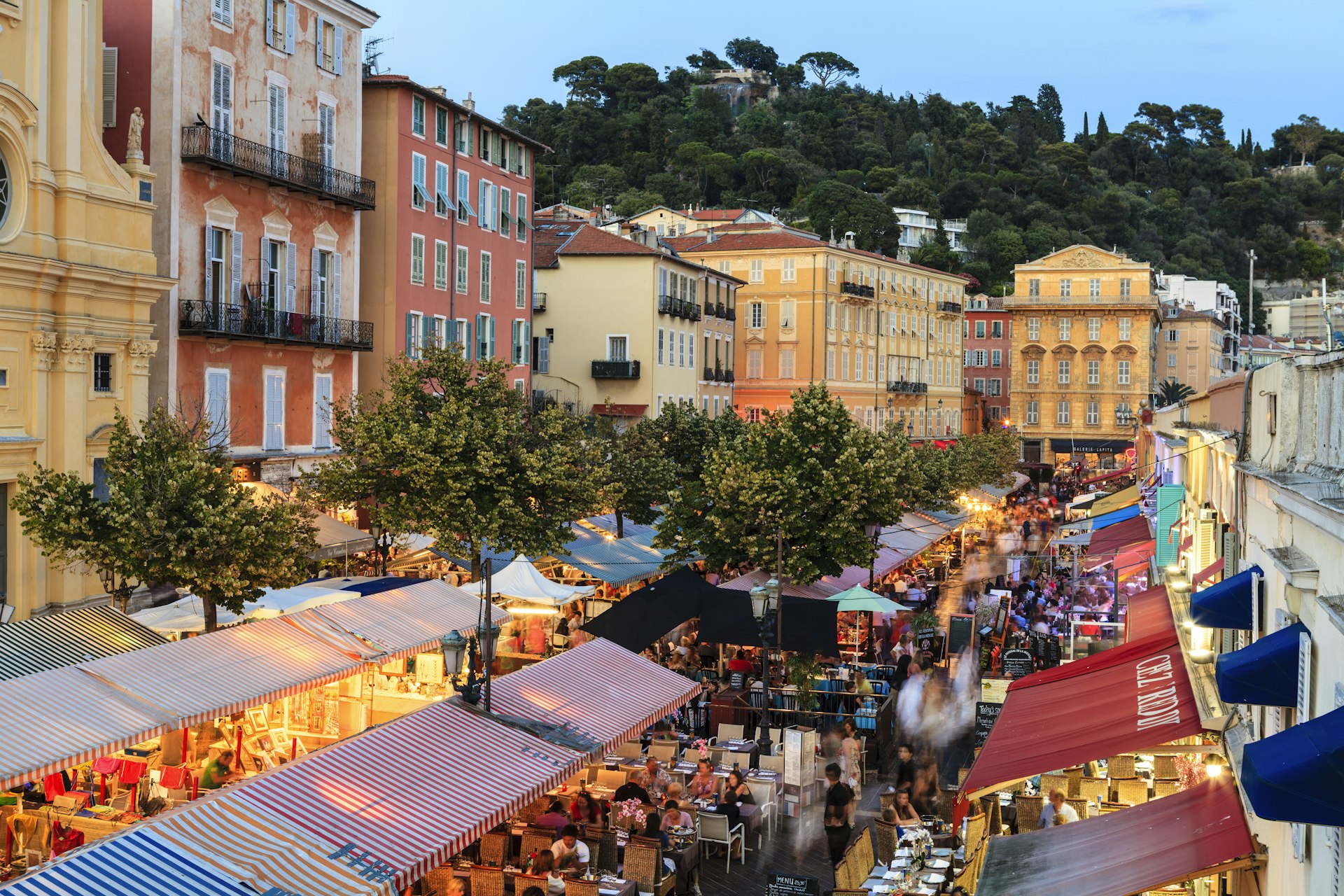 An evening view of colorful buildings and open air restaurants in Nice, France. 