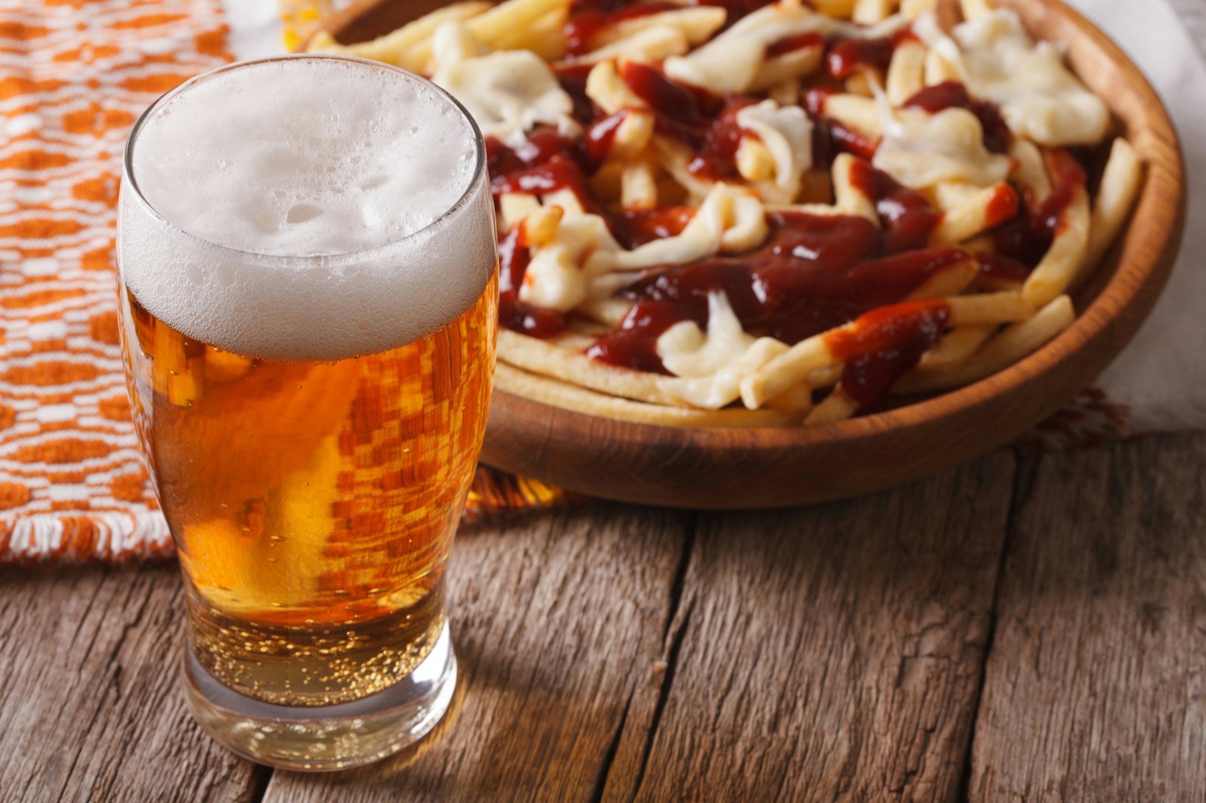 Canadian food: beer and fries with sauce close-up on the table