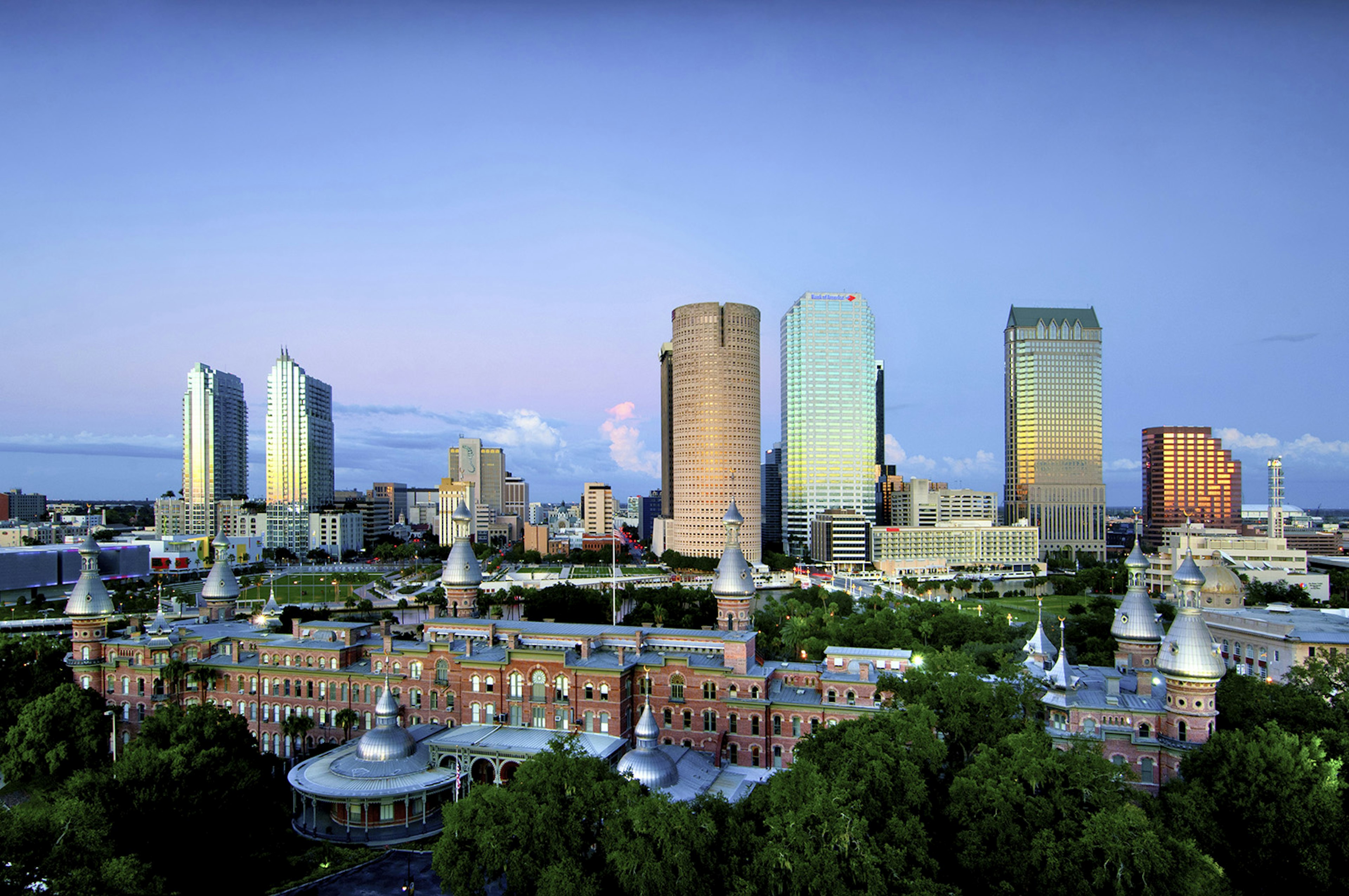 Tampa, Florida, downtown skyline. Foreground is the red-bricked building of the historic Plant Hall Of The University Of Tampa. Glass skyscrapers reflecting a sunset tower over it in the background © John Colletti / Getty Images