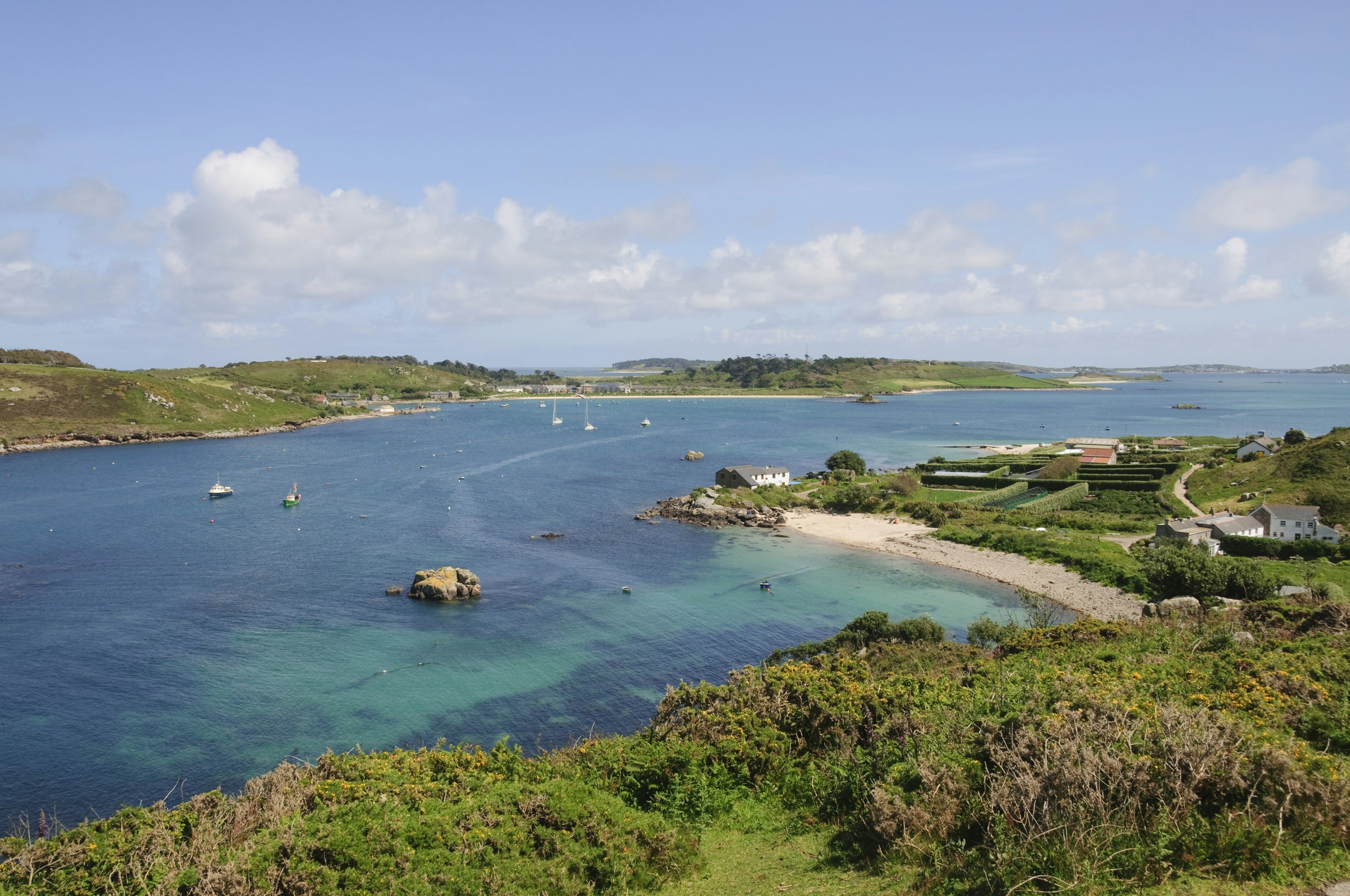 A view overlooking the shallow turquoise waters off the coast of Bryher, with neighbouring Tresco island in the background.