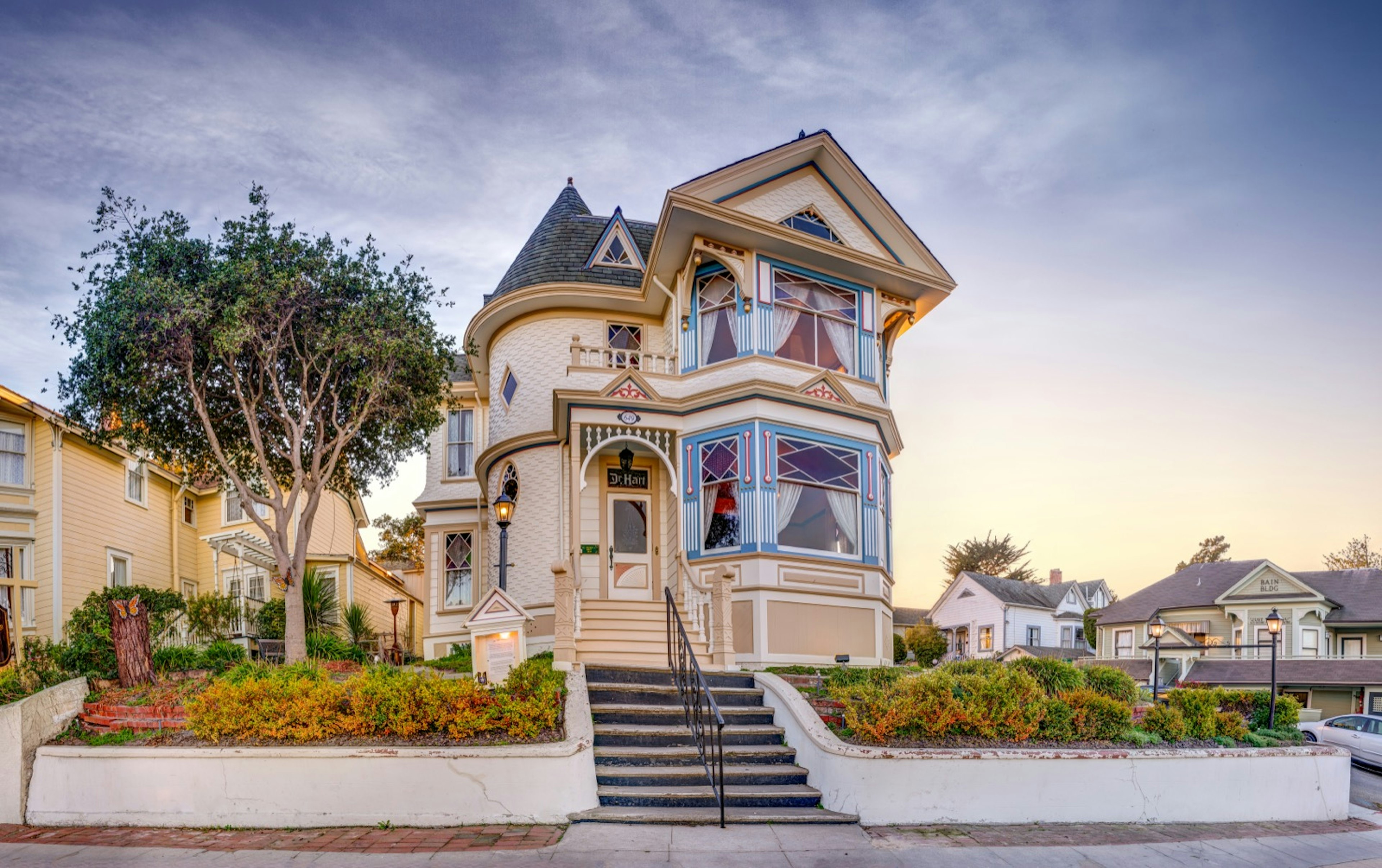 A victorian mansion painted with blue and red details on a street corner in Pacific Grove near Monterey