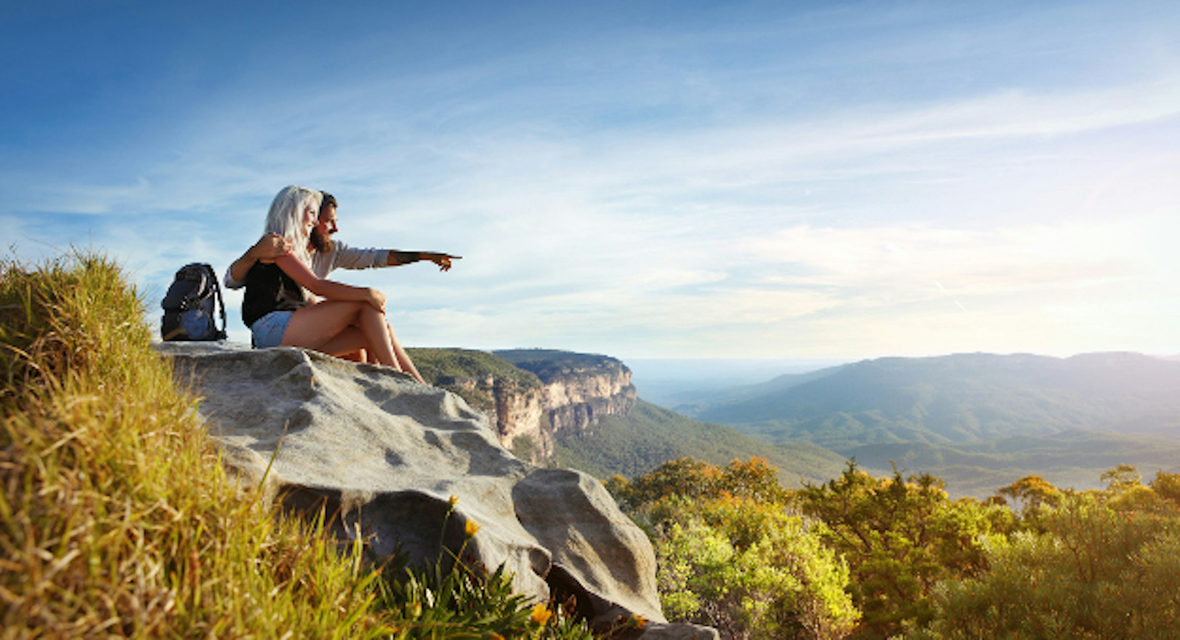 Young traveling couple having rest on the rock and enjoying view in Blue Mountains in Australia.