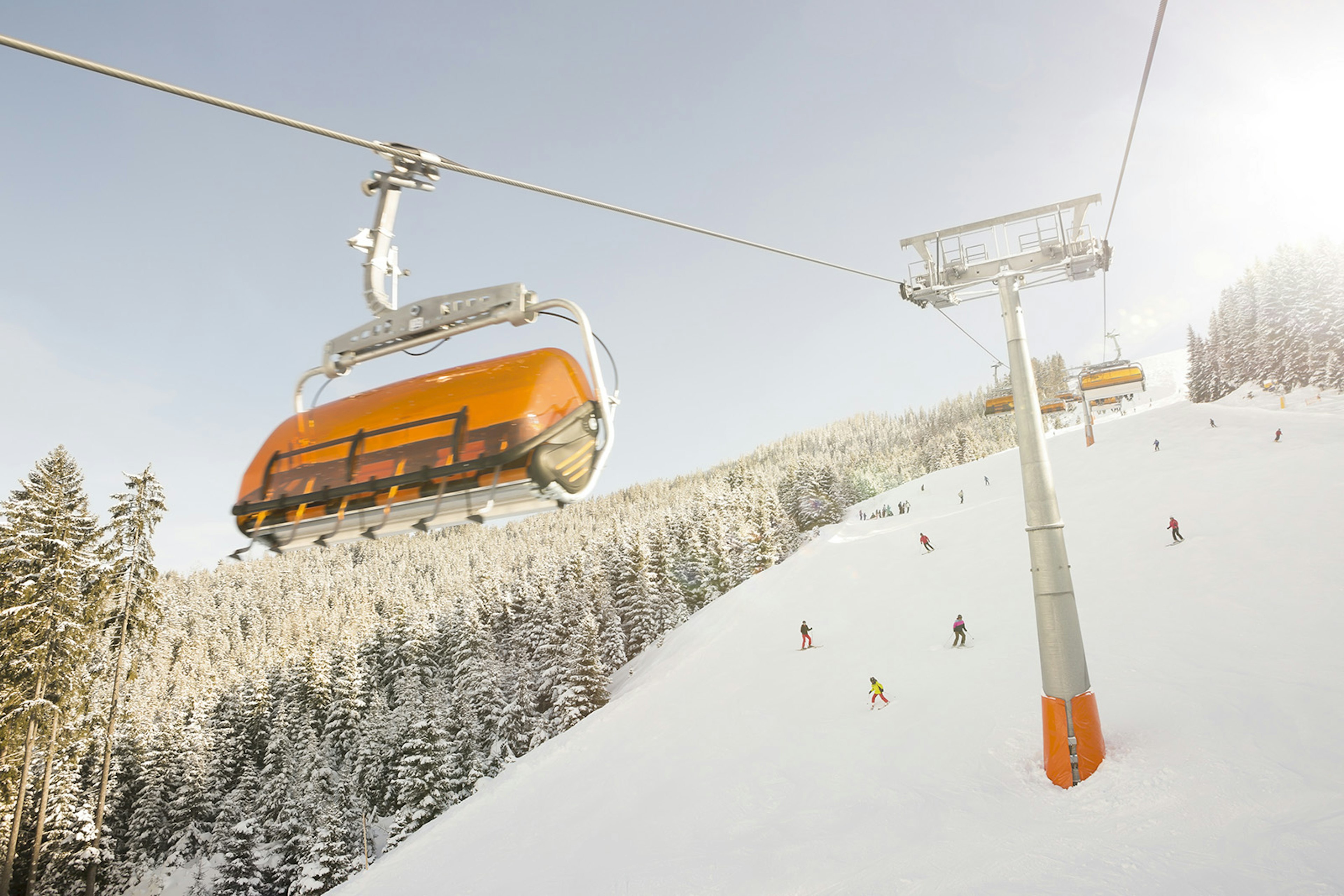 An empty yellow ski lift coming down from the snowy mountains