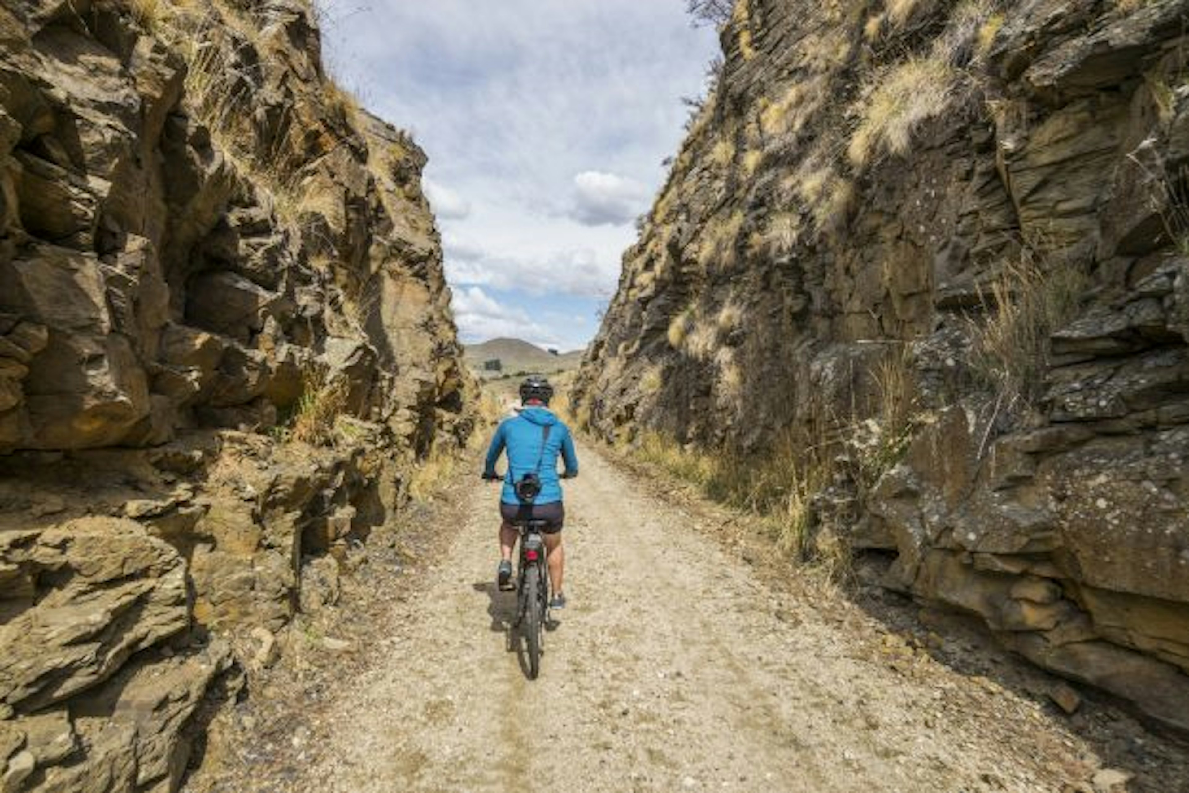 Cycling through a cutting on Otago Rail Trail, South Island, New Zealand.