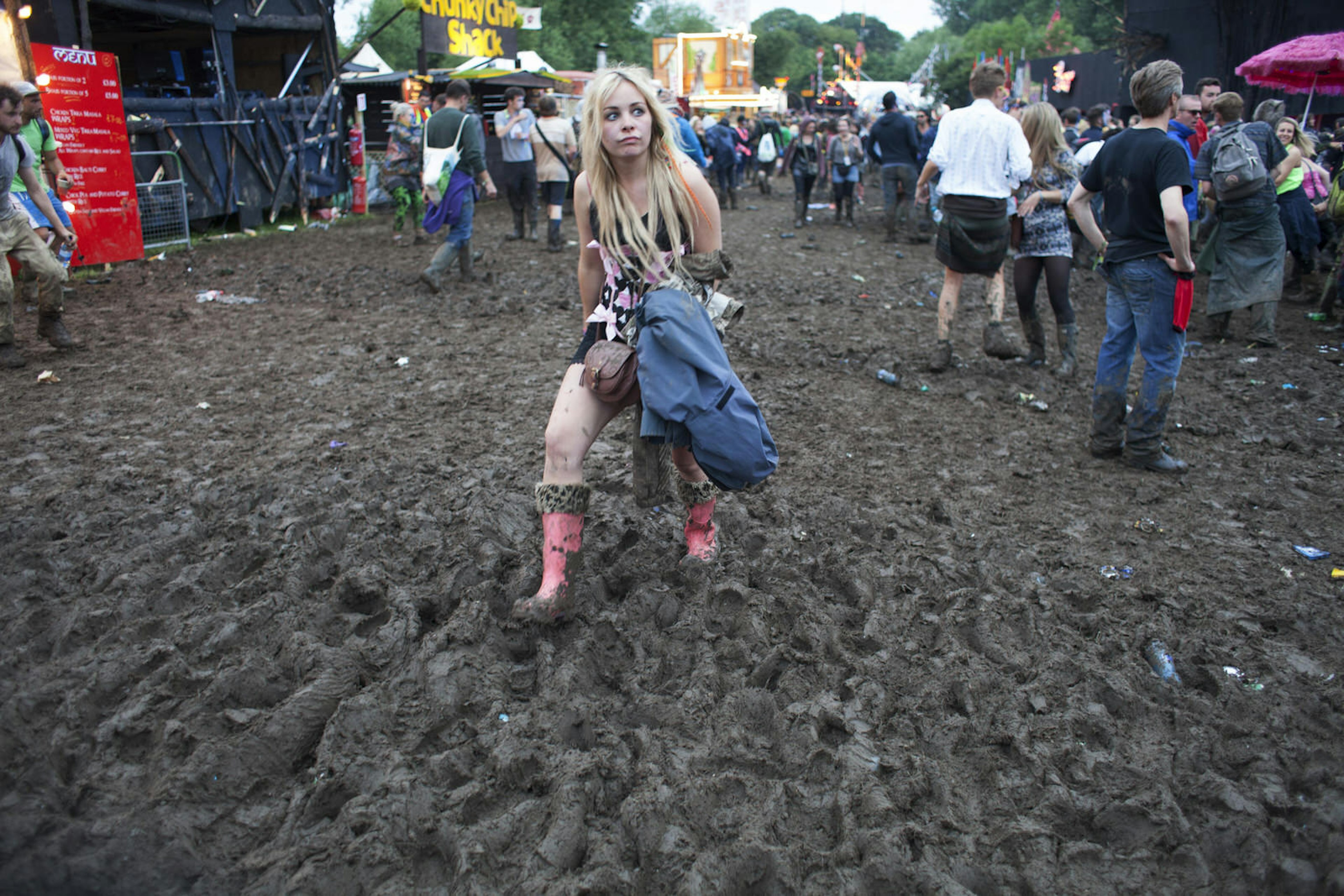 A woman walking through thick mud wearing wellies